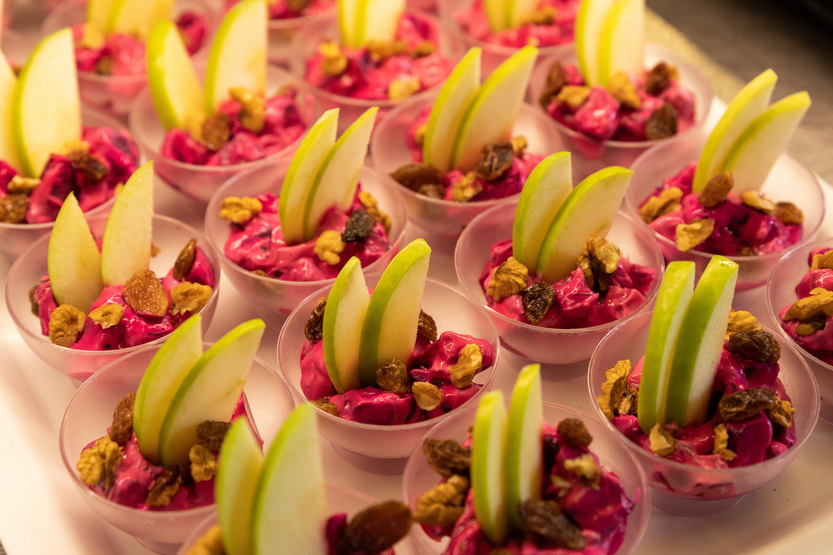 Individual beetroot salad cups with green apple, walnuts, and raisins.