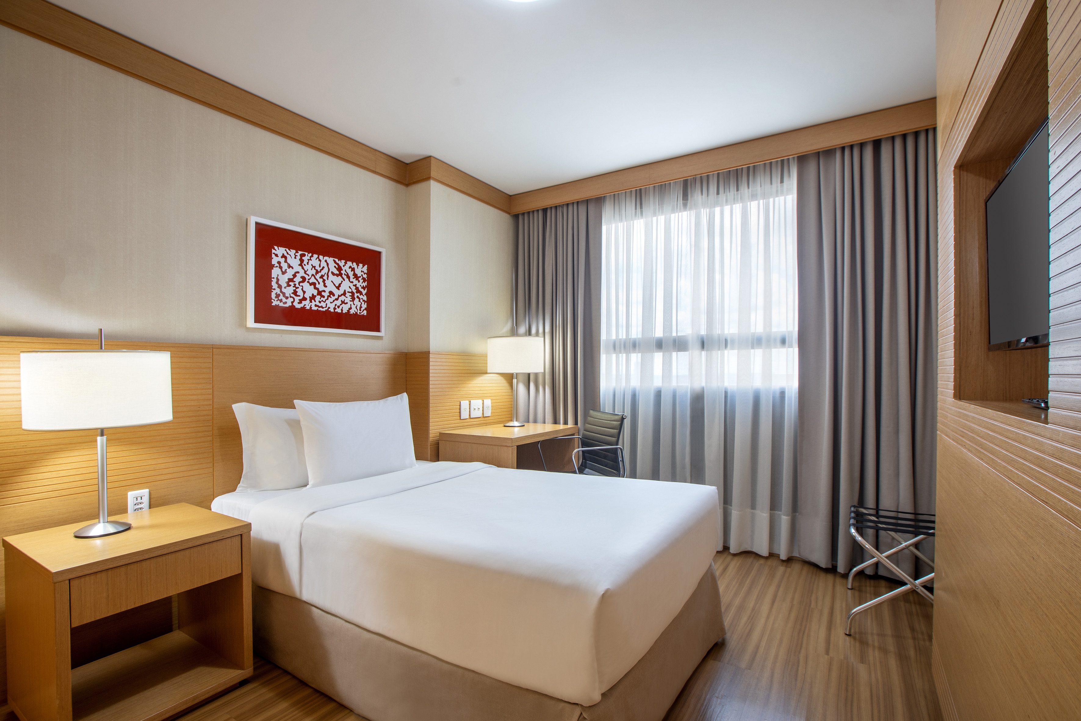 Modern hotel room with single bed, work desk, and TV.