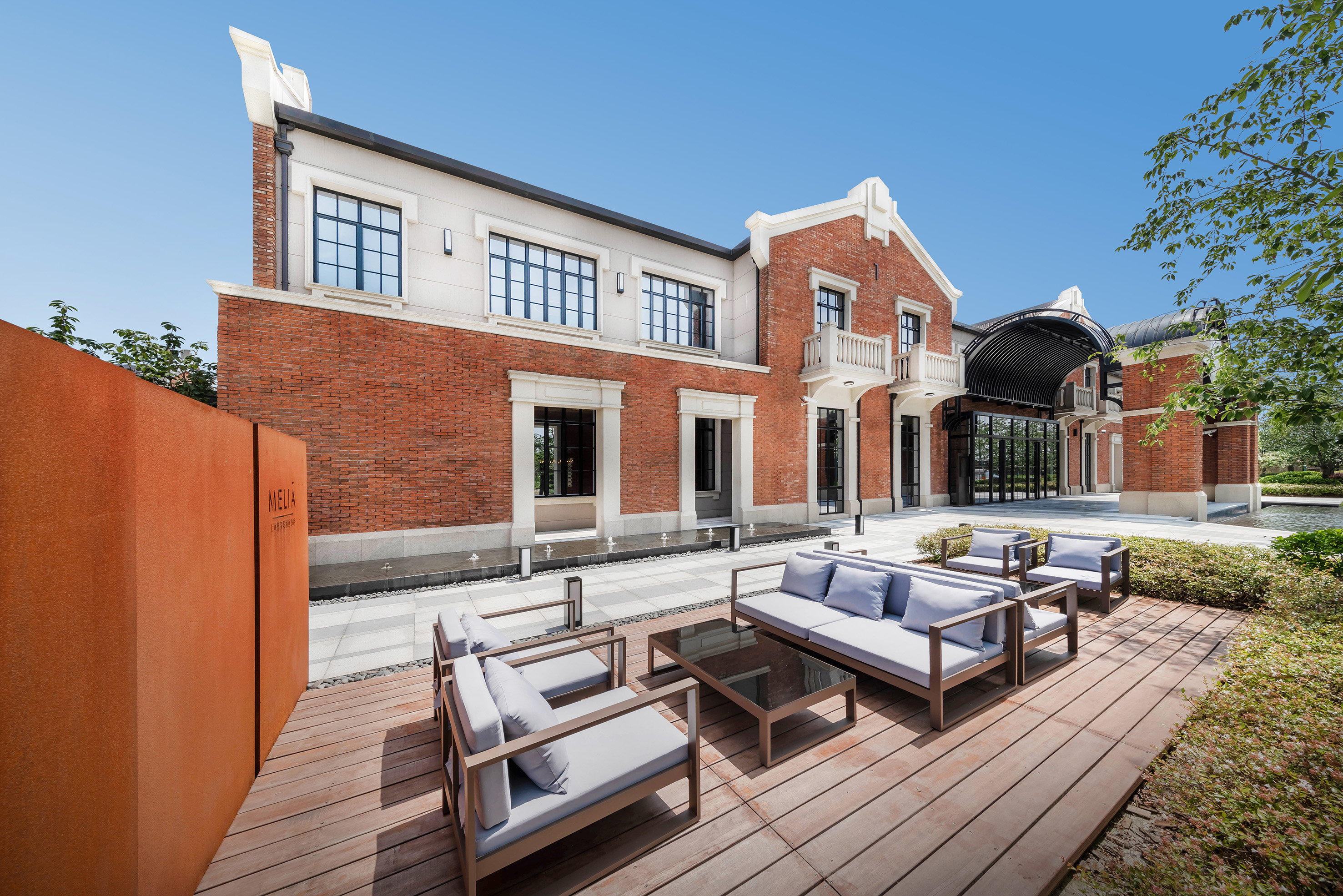 Meliá hotel patio with modern outdoor furniture and red brick building facade.