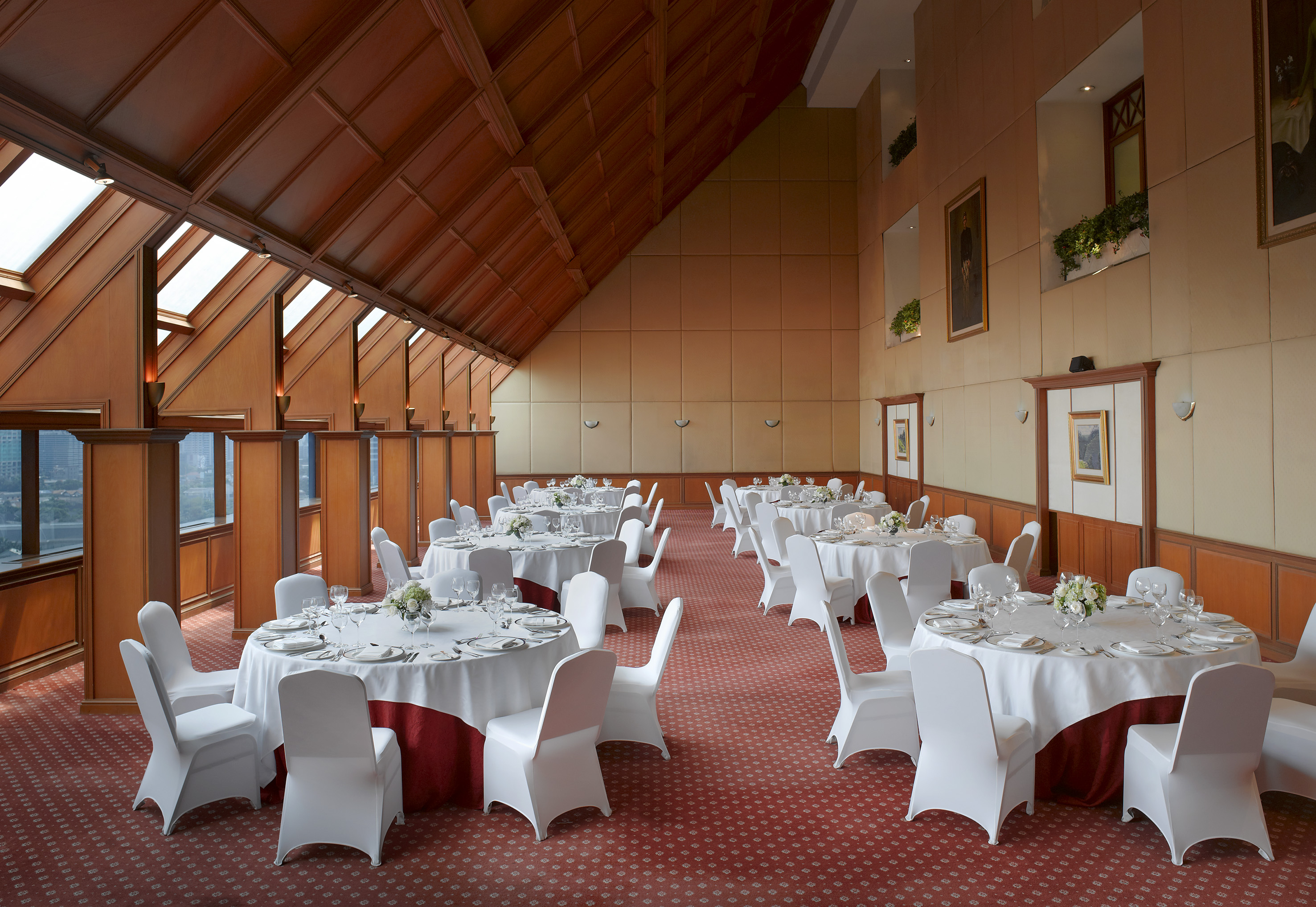 Ballroom for events: round dining tables, white chairs, and wooden ceiling.