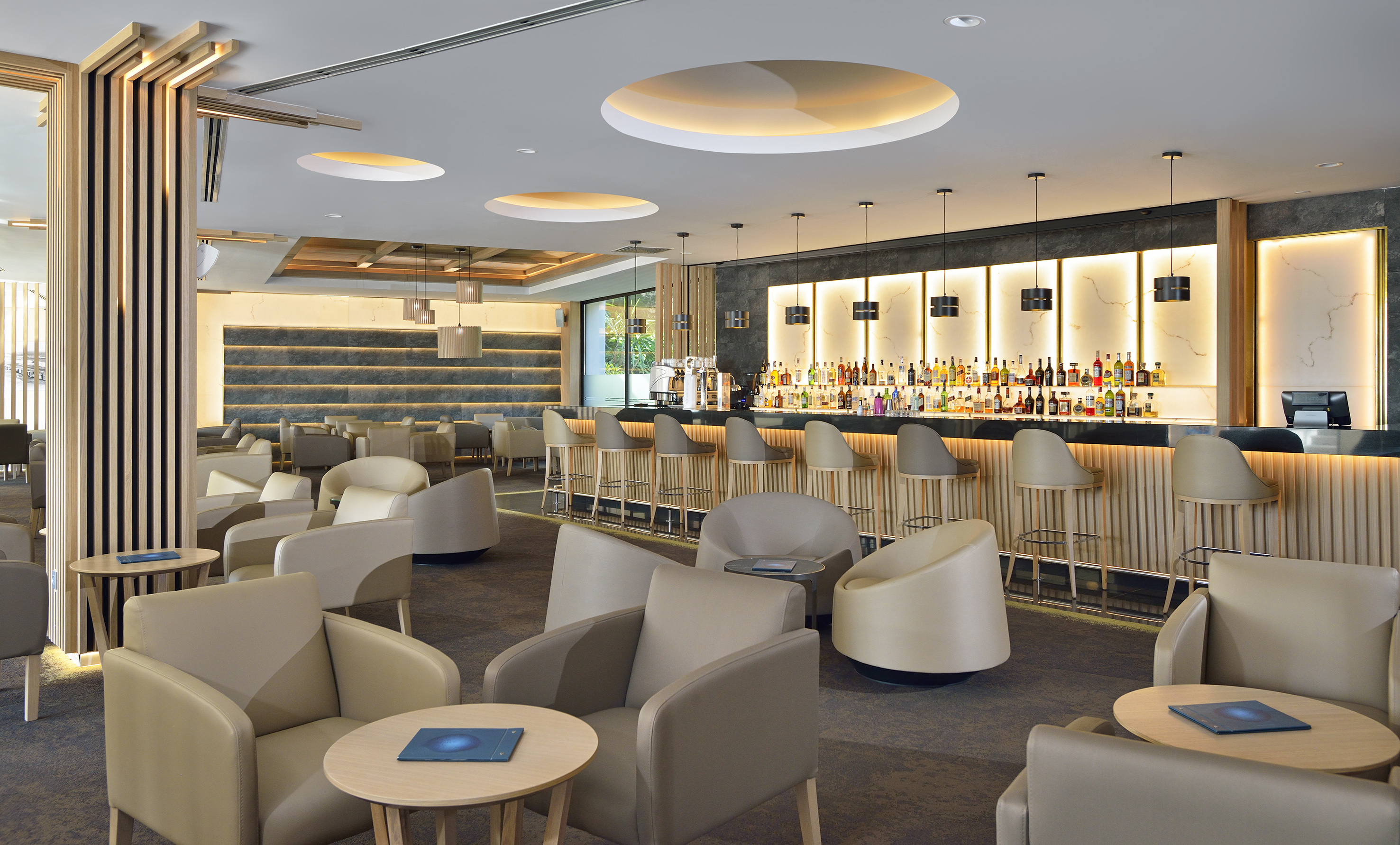 Modern bar interior featuring liquor bottles, bar stools, and lounge seating.