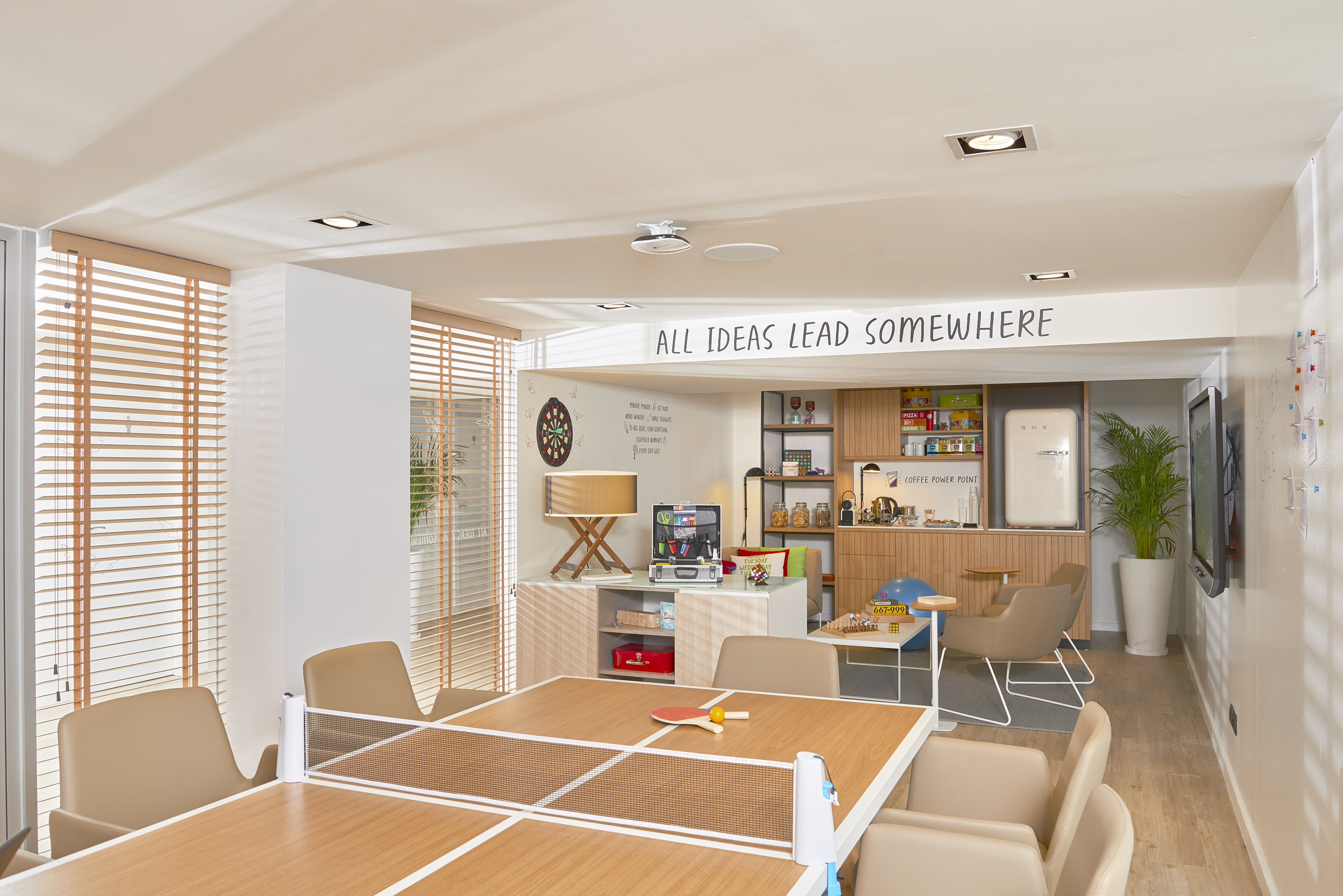 Office break room with ping-pong table, kitchenette, and creative decor.