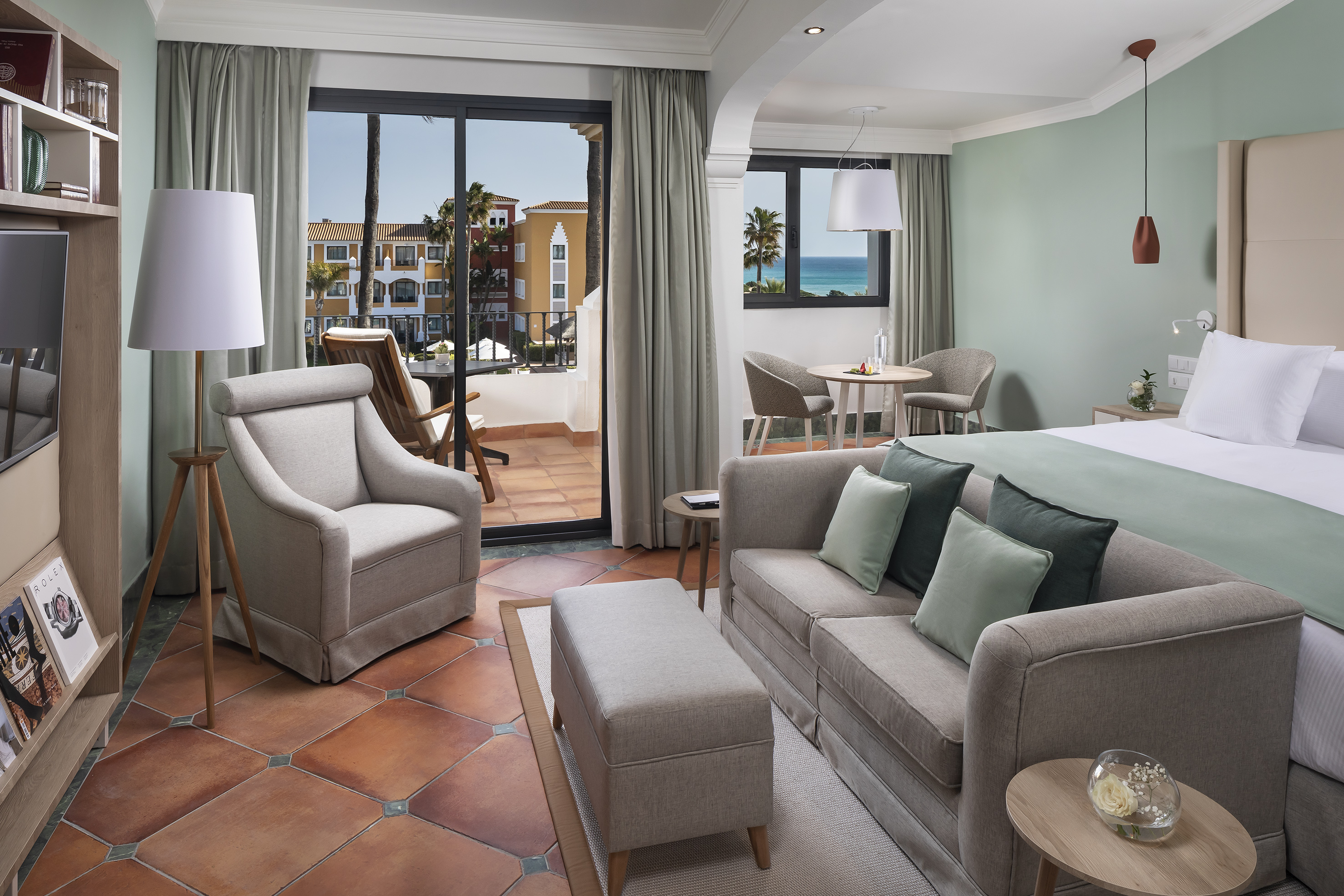 Luxury hotel suite with ocean view, living room, bedroom, and balcony.