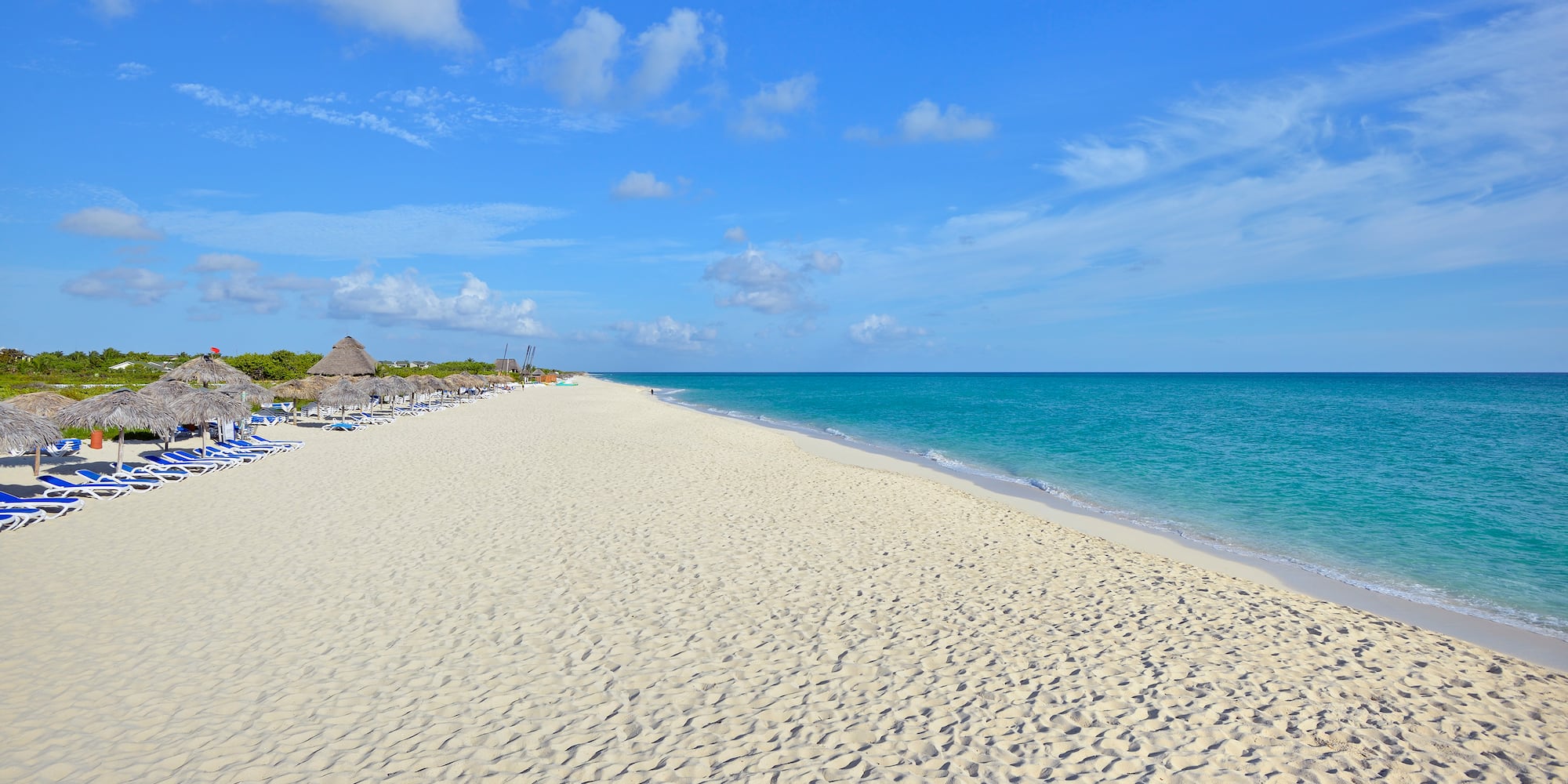 a beach with blue water and clouds