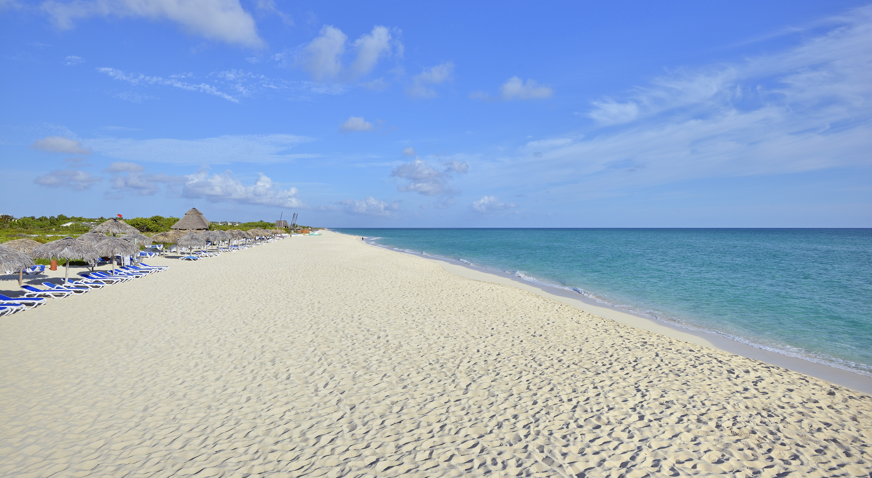 a beach with blue water and clouds