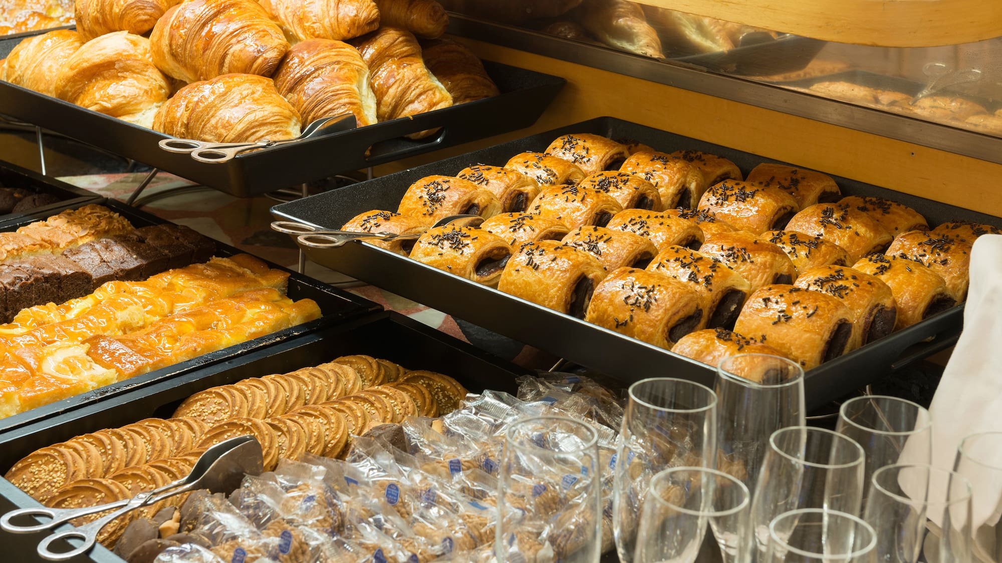 a trays of pastries and glasses on a shelf