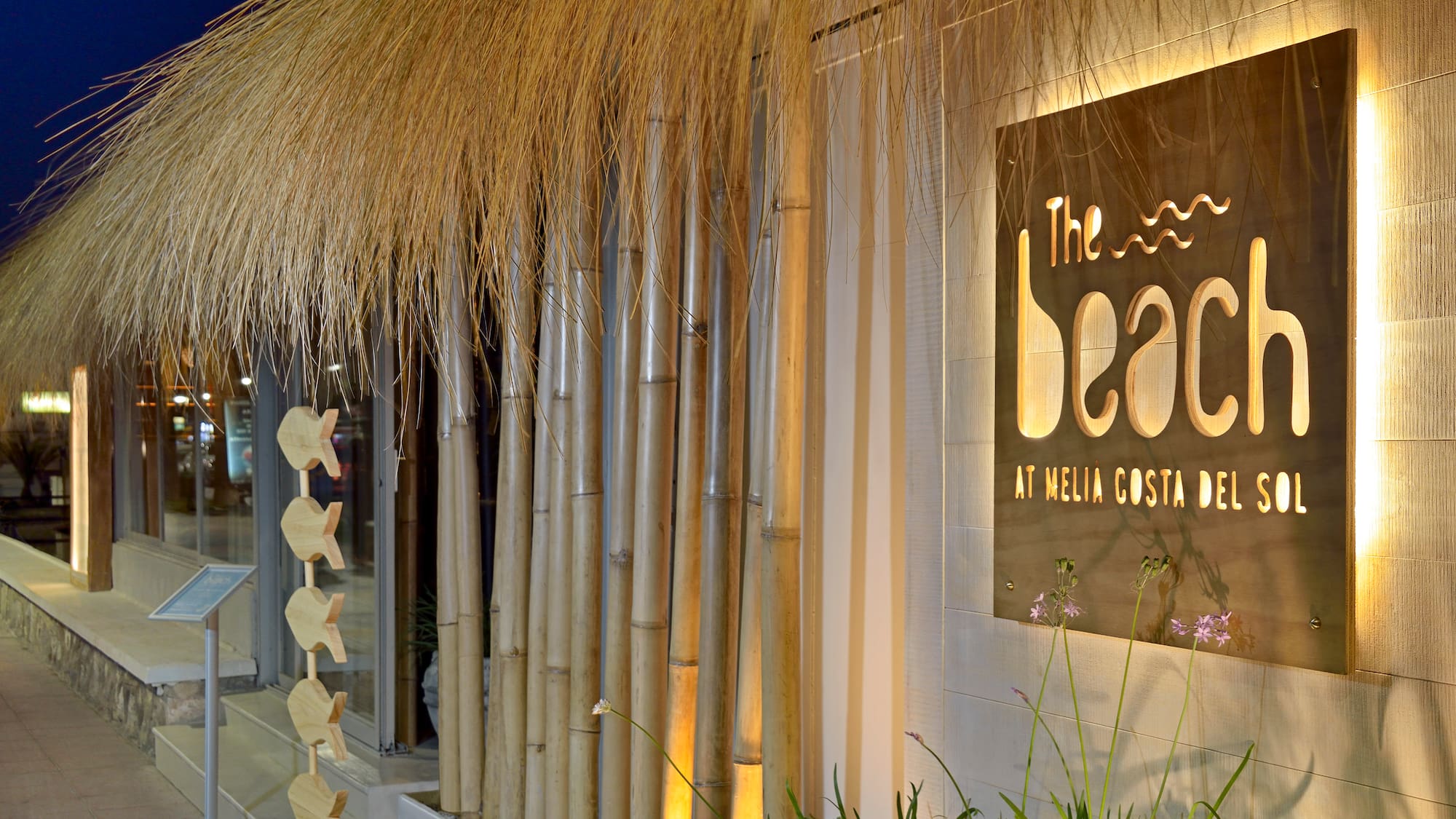 a building with a thatched roof and bamboo poles