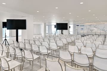a room with white chairs and a screen