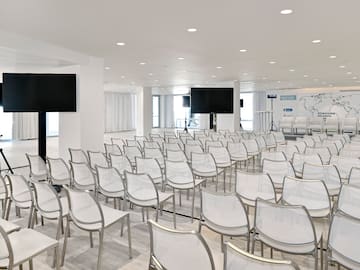a room with white chairs and a screen