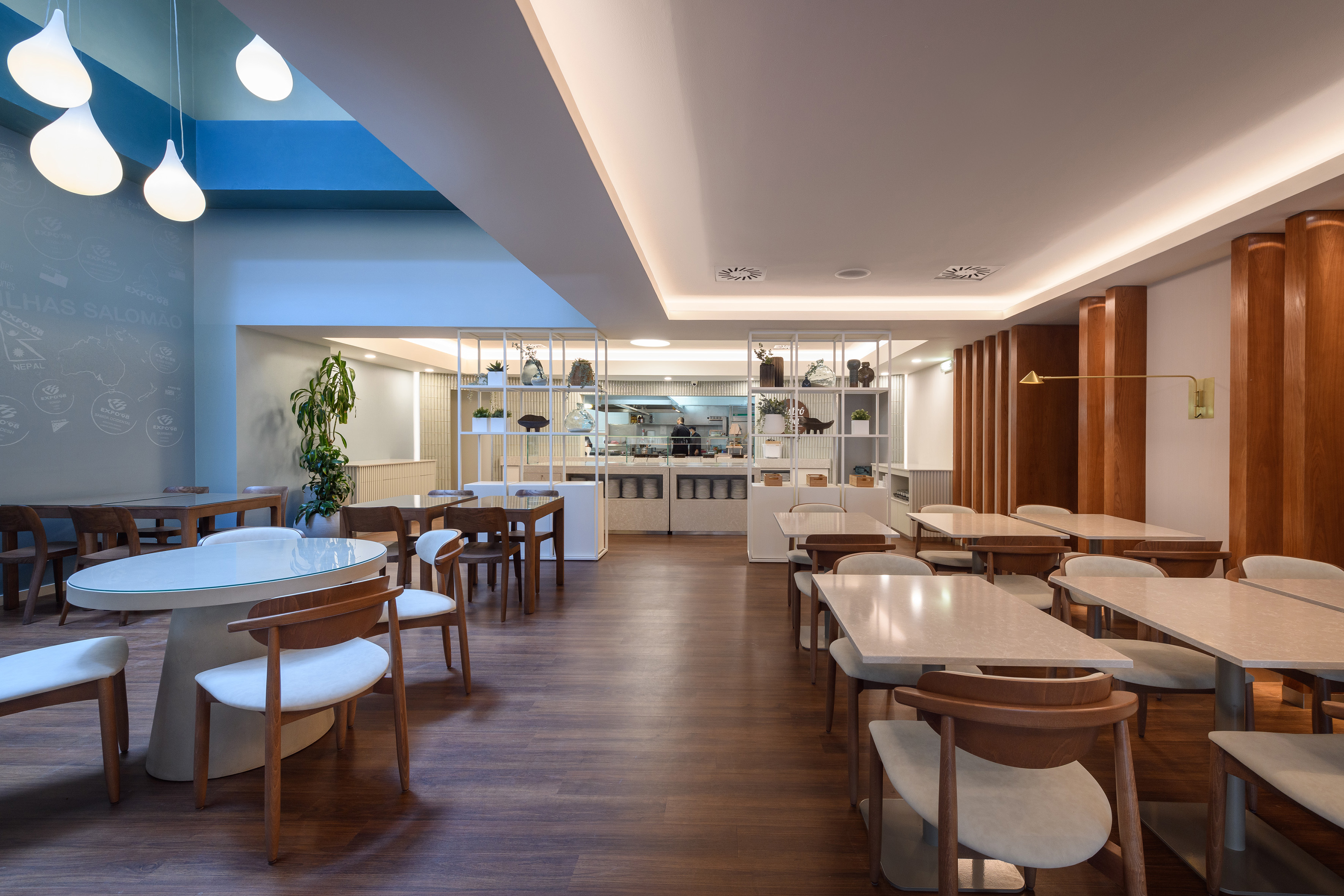 Contemporary restaurant with light tables, wooden chairs, and buffet station.