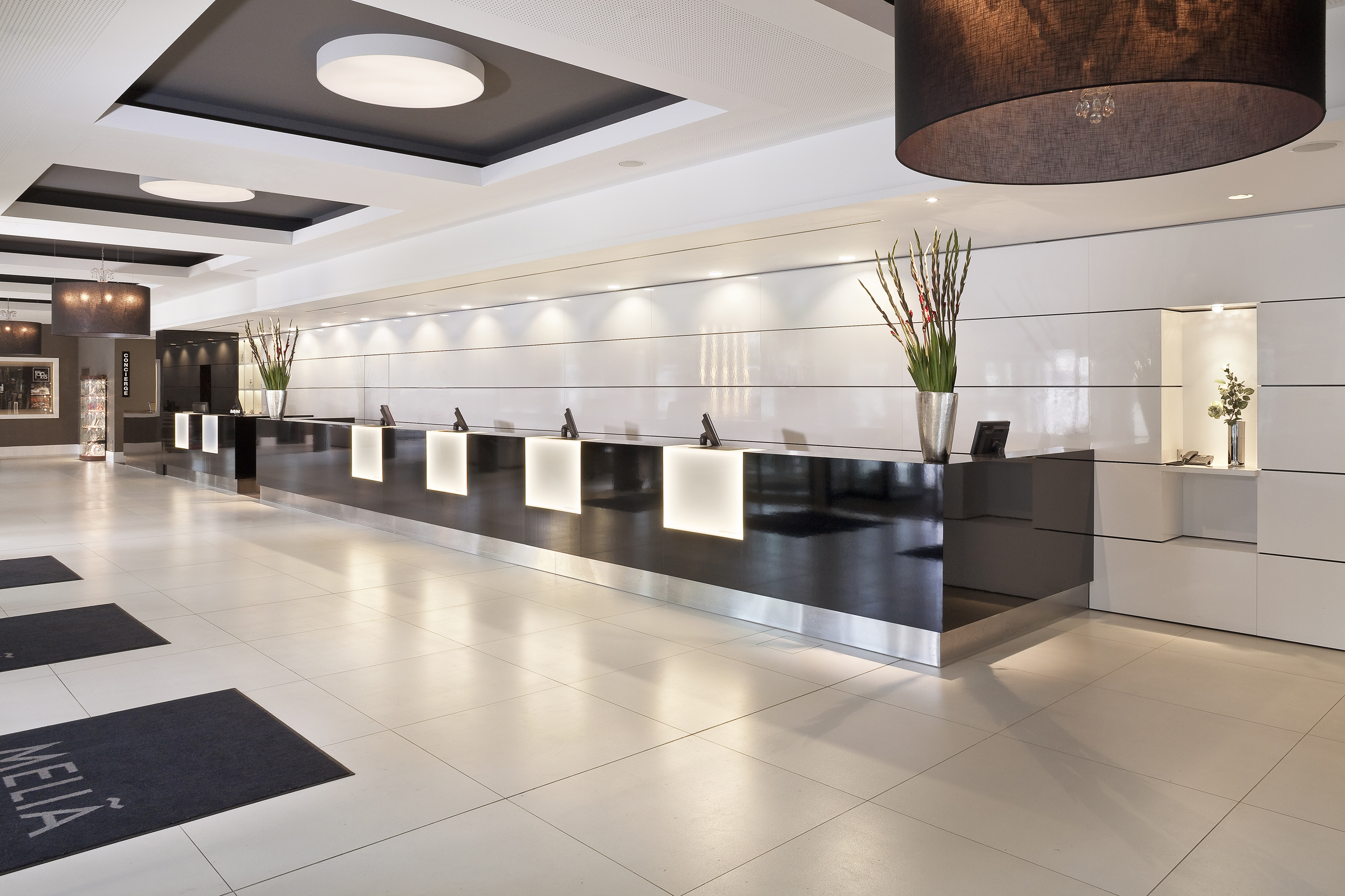 Meliá hotel lobby with modern black reception desk, sleek design, and bright lighting.