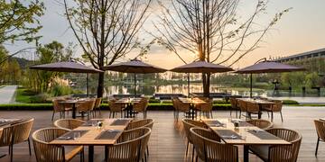a group of tables and chairs on a deck with umbrellas
