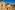 Beige church with blue patterned dome, clock tower, and terracotta roofs in sunny town.