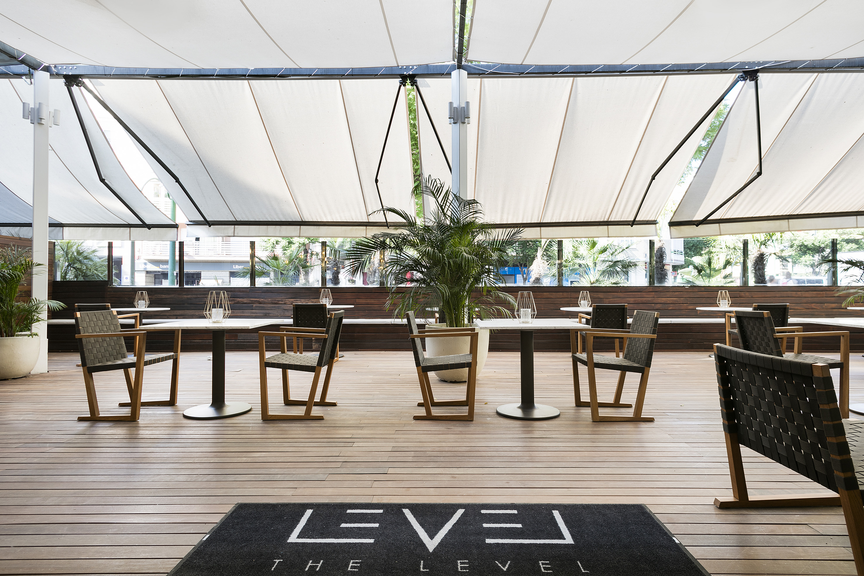 Outdoor restaurant patio with retractable awning, wooden deck, and modern tables.