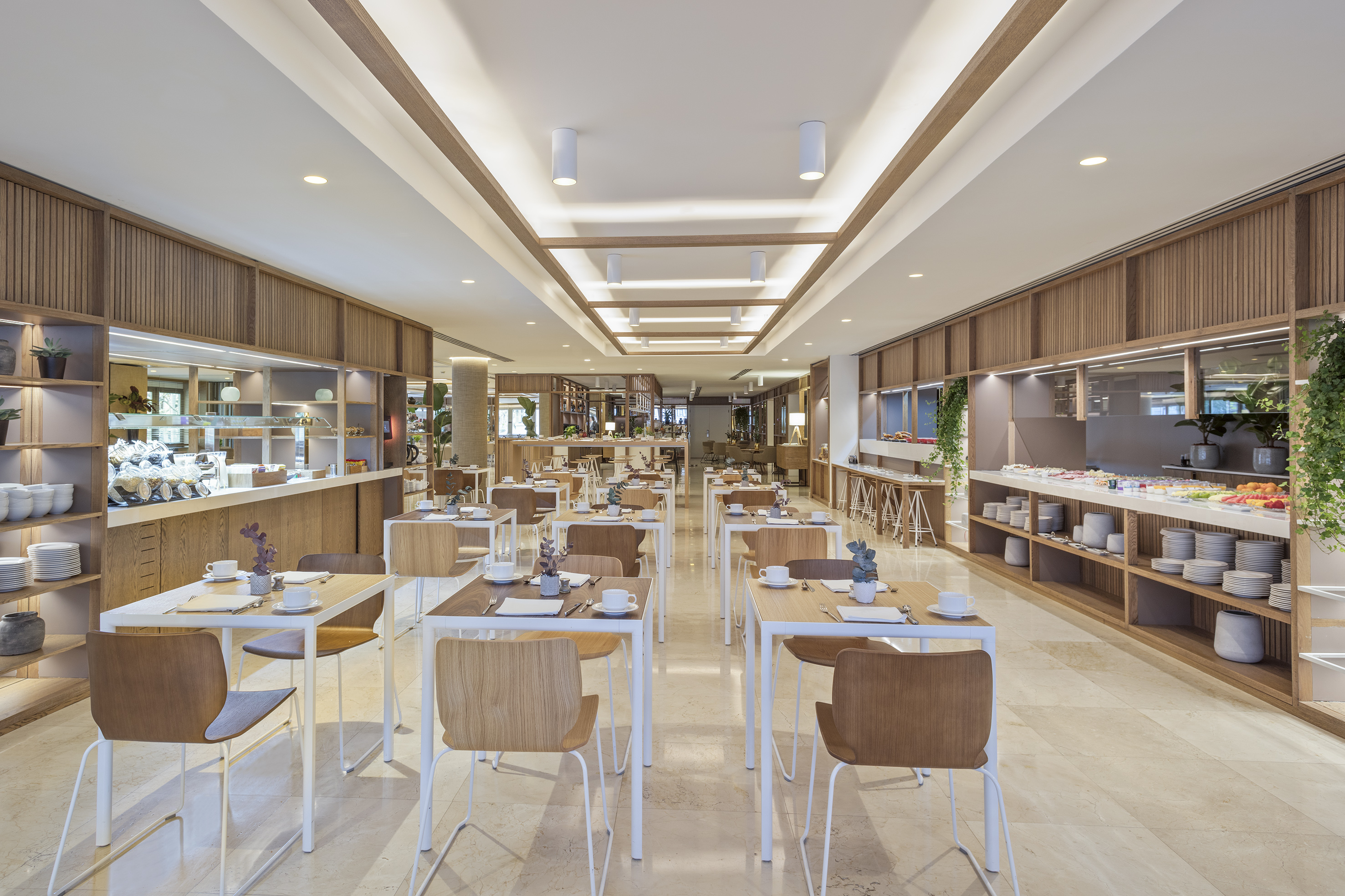 Spacious, modern hotel dining room with set tables and buffet service.