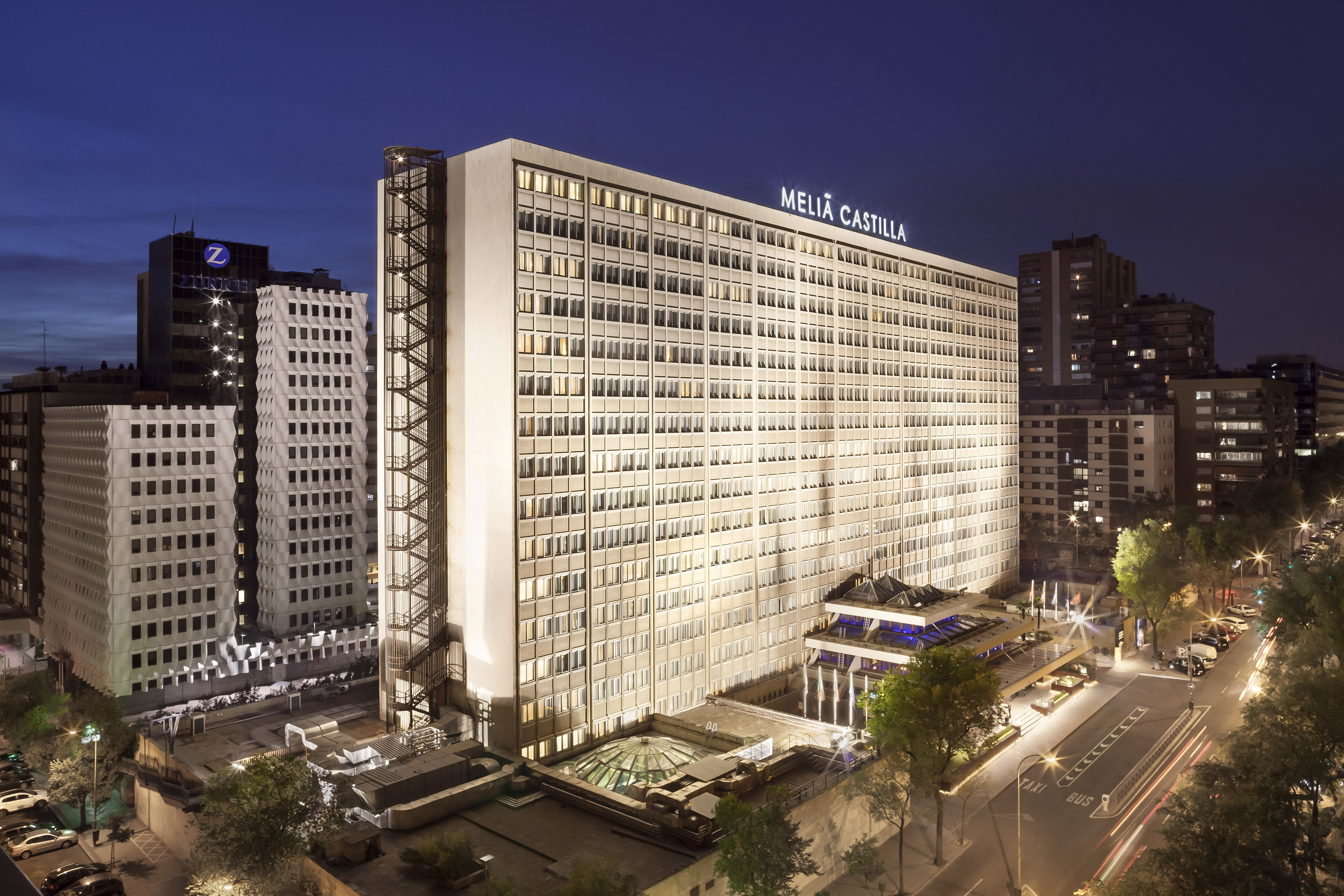 Meliá Castilla hotel, illuminated modern building at night with city street.