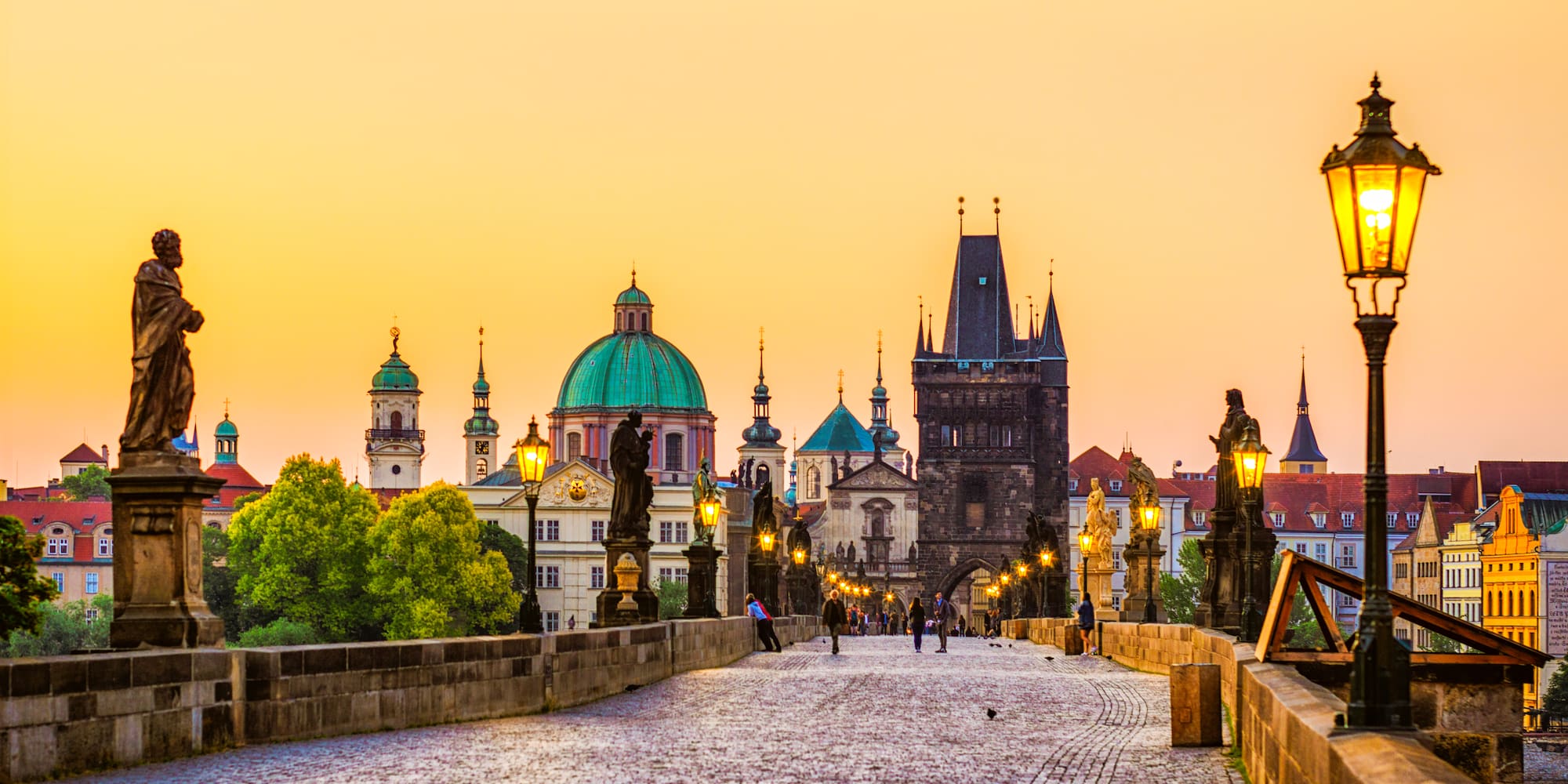 a stone bridge with statues and a city in the background