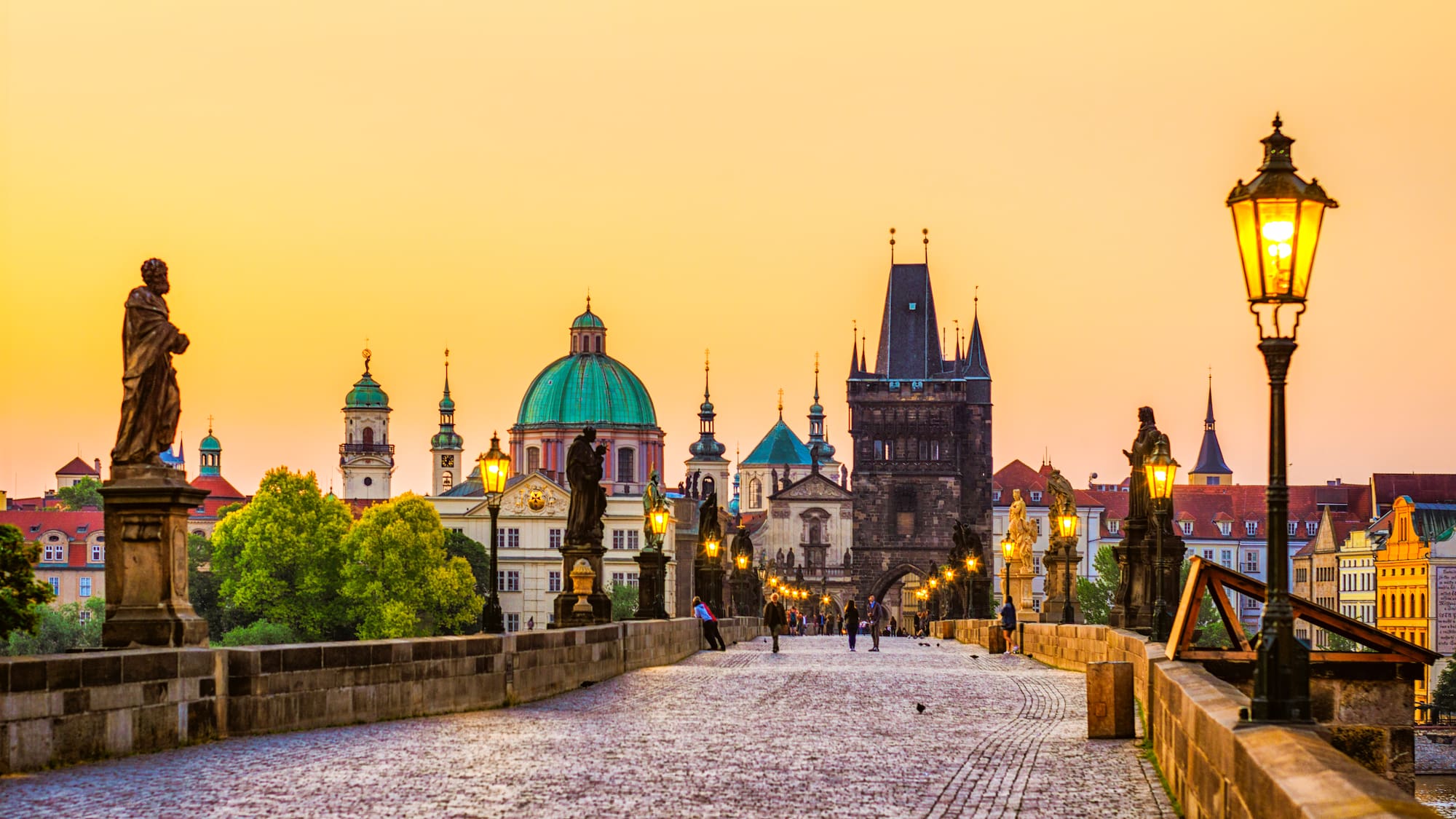 a stone bridge with statues and a city in the background