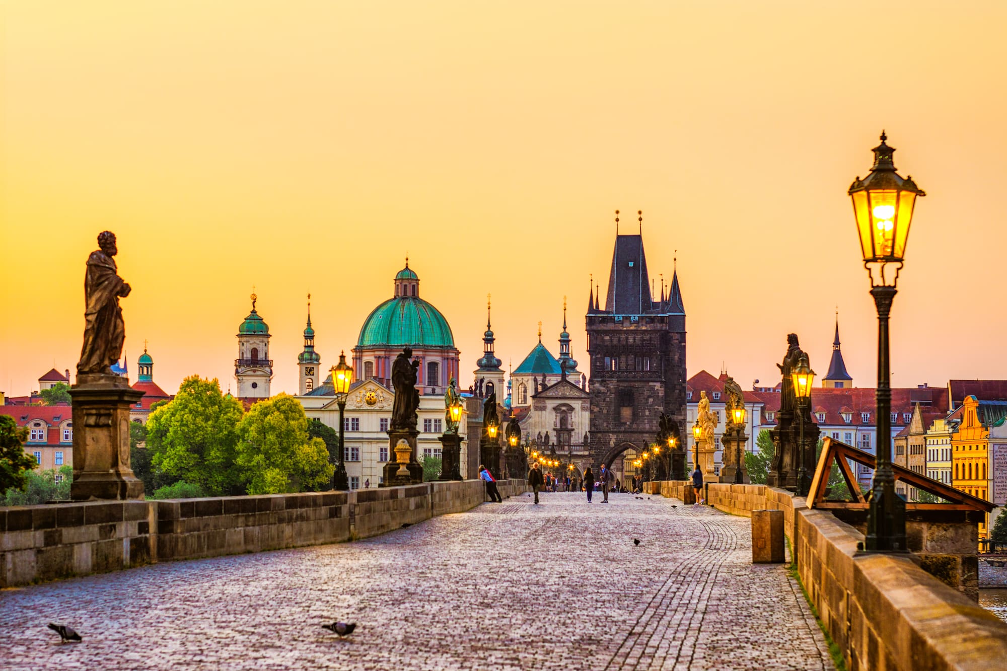 a stone bridge with statues and a city in the background