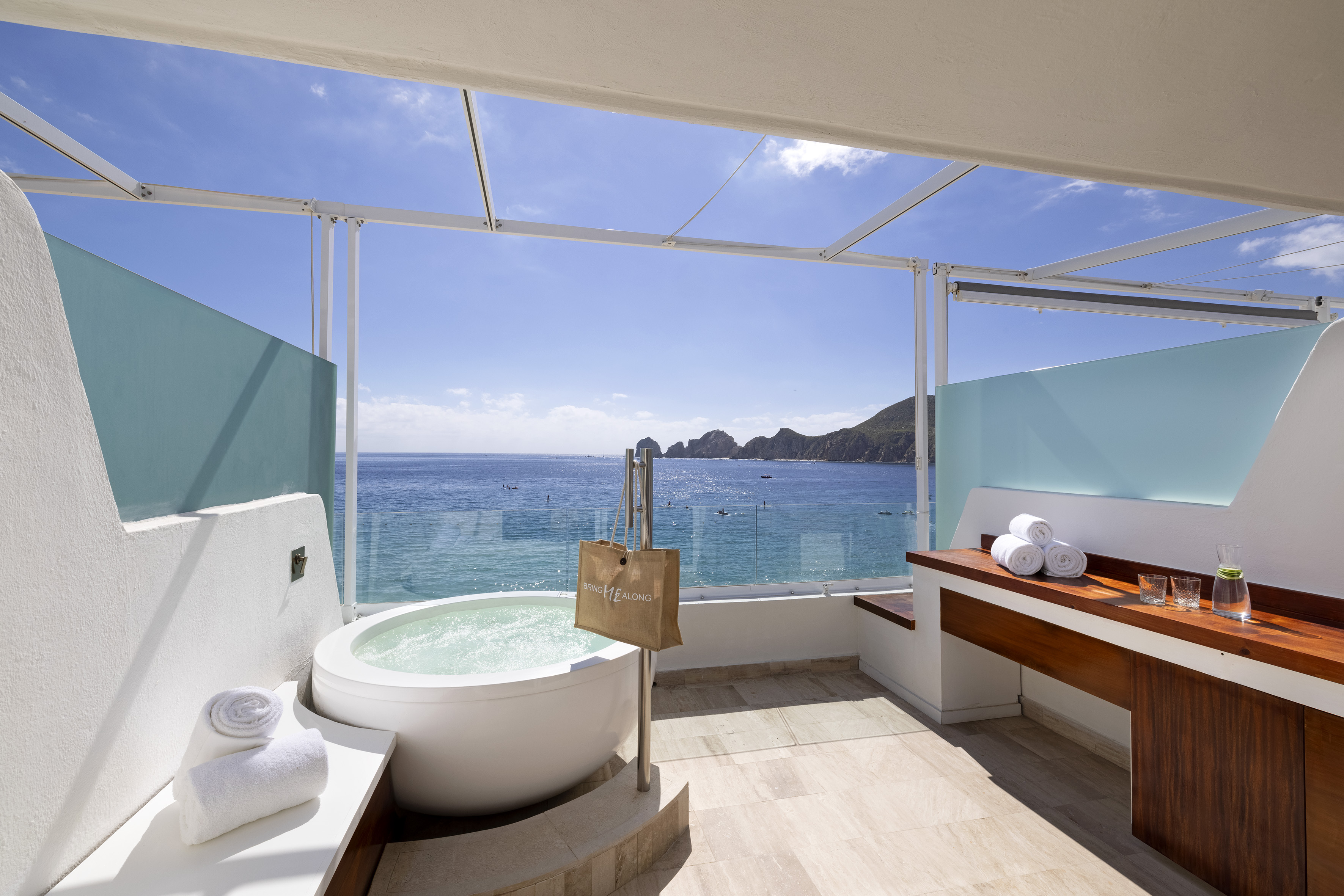 a bathroom with a tub and a large window overlooking the ocean
