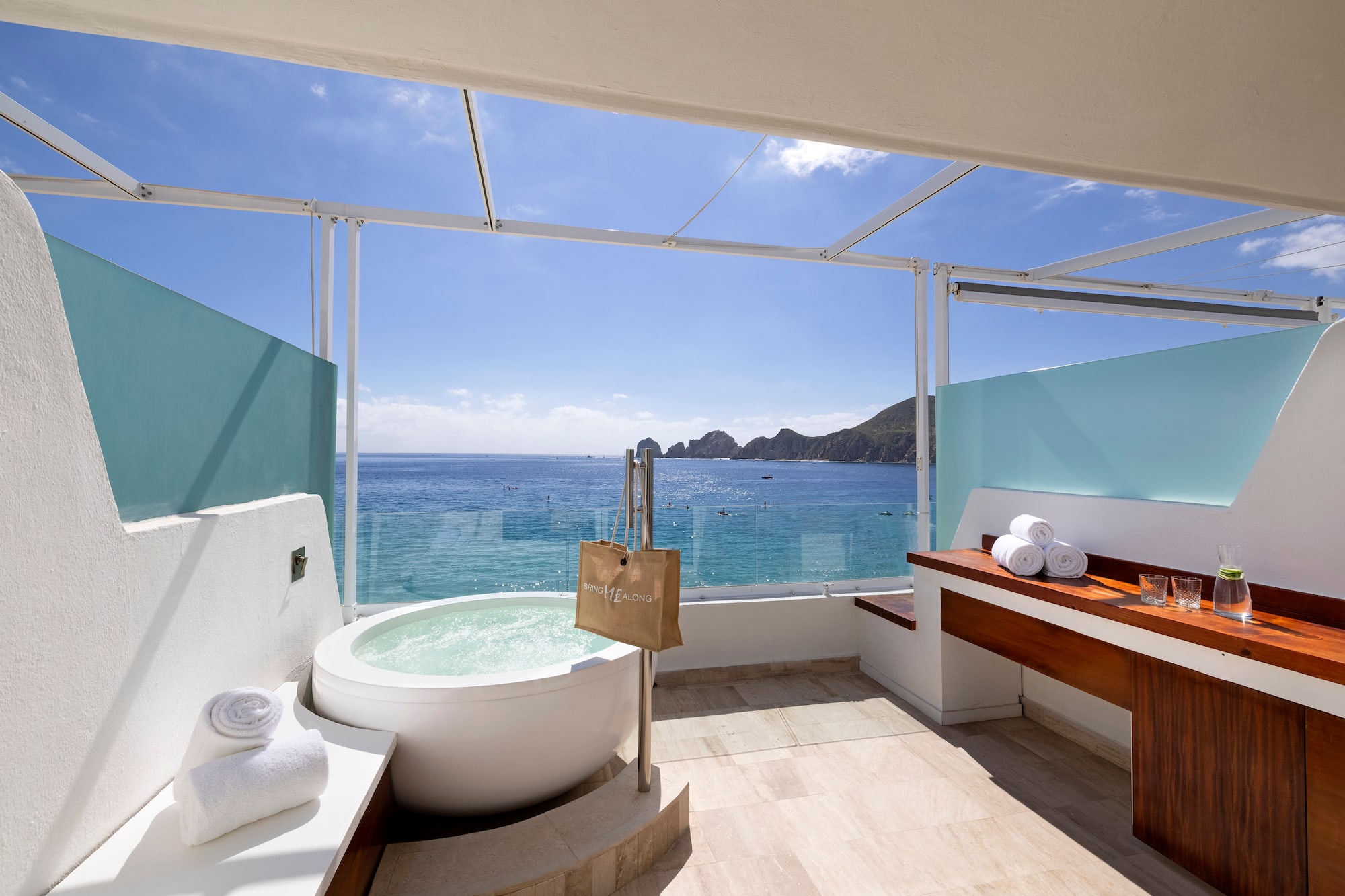 a bathroom with a tub and a large window overlooking the ocean