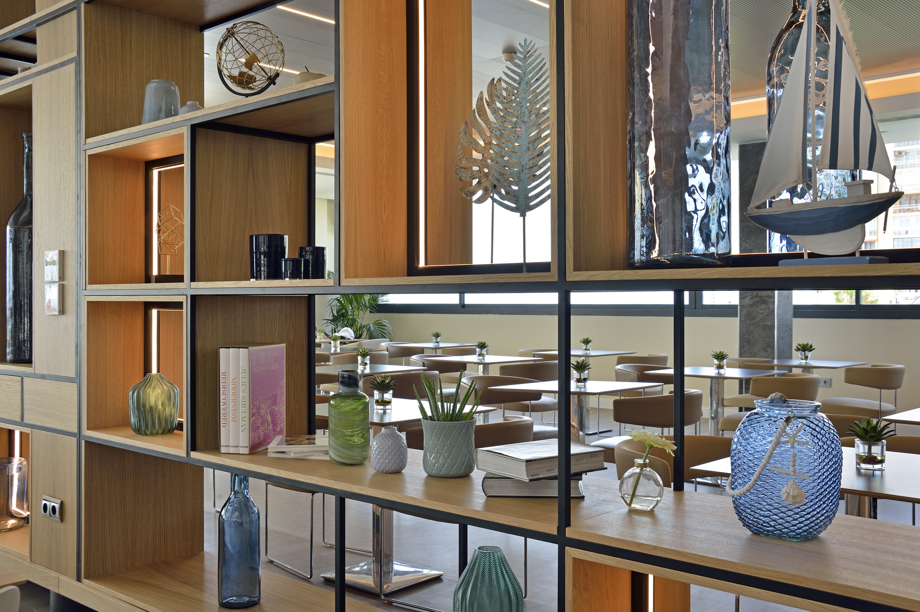 Modern wooden shelving unit with decor, dividing a stylish cafe dining area.