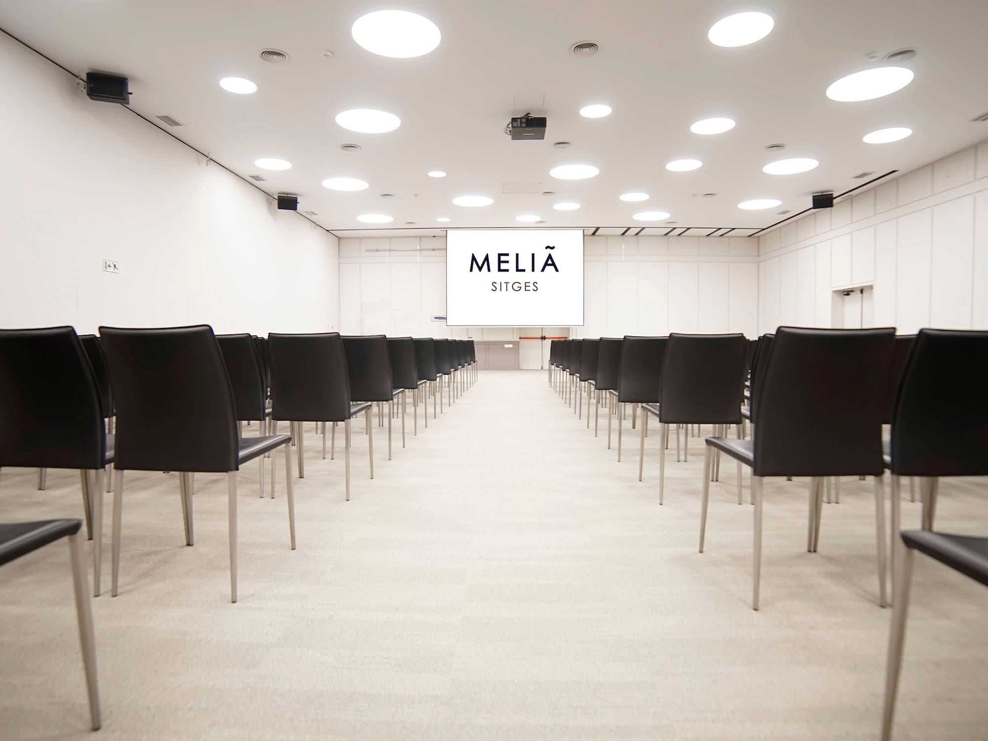 a room with black chairs and a white screen