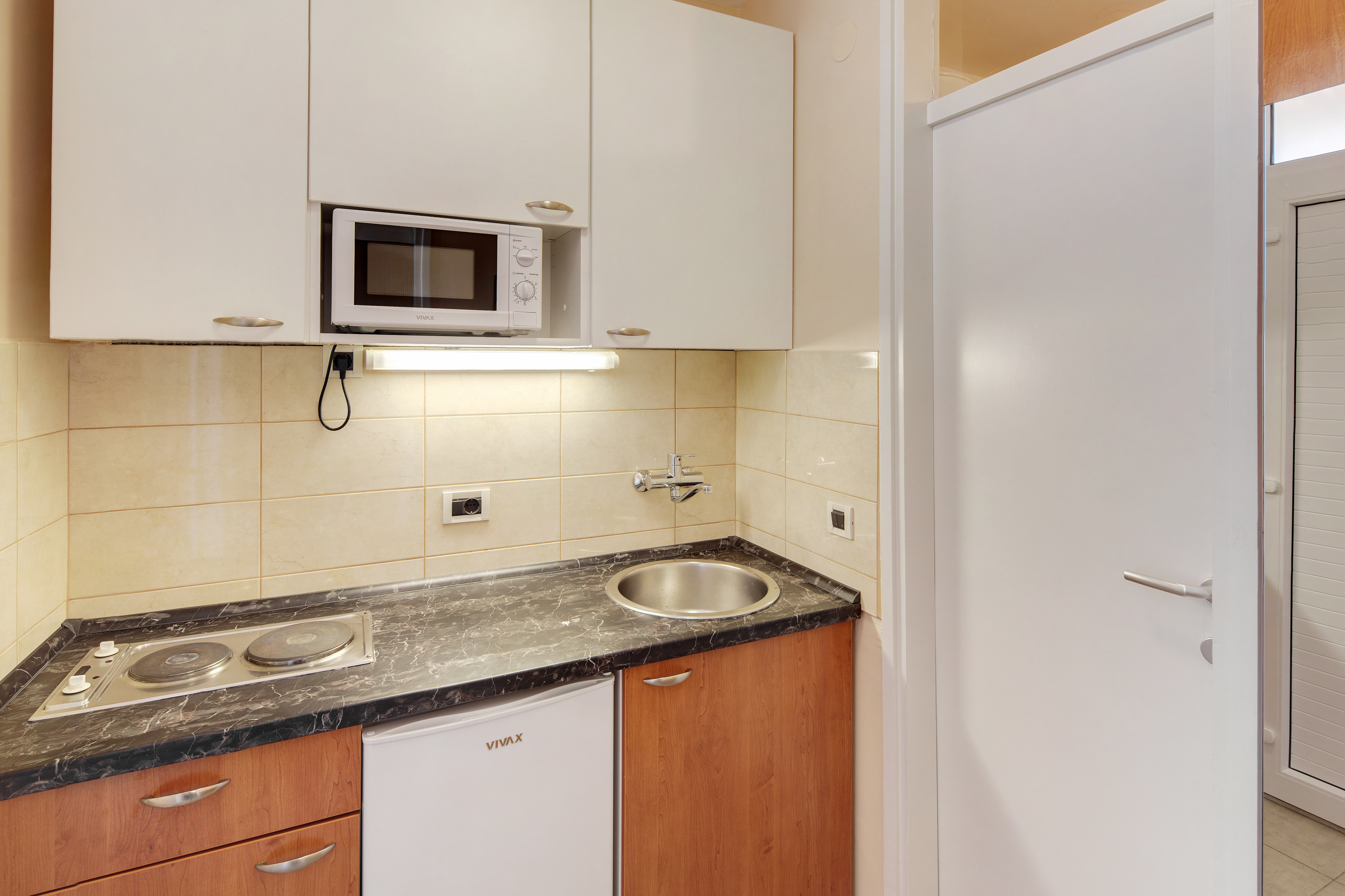 a kitchen with white cabinets and a microwave - Stella Superior - Apartments Stella Plava Laguna este afiliată Meliá, Umag