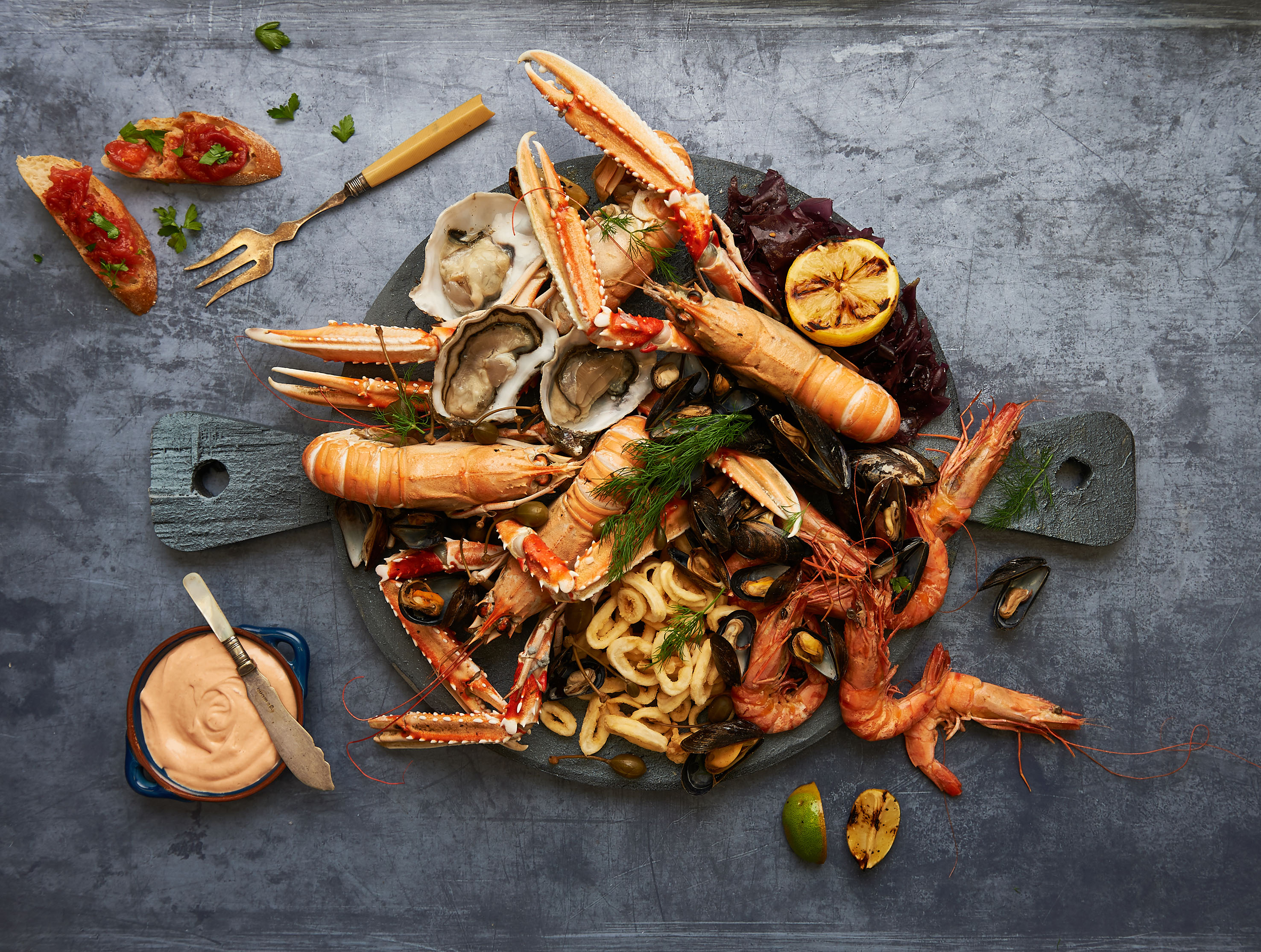 Fresh seafood platter with oysters, langoustines, prawns, mussels, calamari, lemon.
