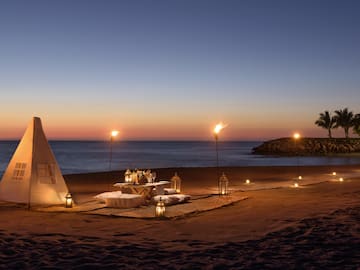a tent and table set up on a beach with lit candles