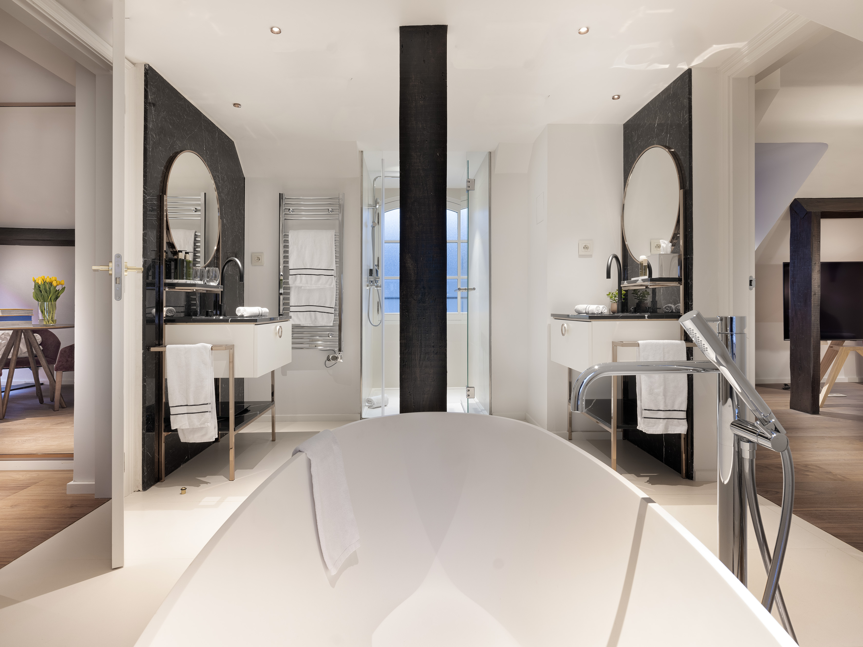 Luxury bathroom with white freestanding tub, dual vanities, and sleek design.