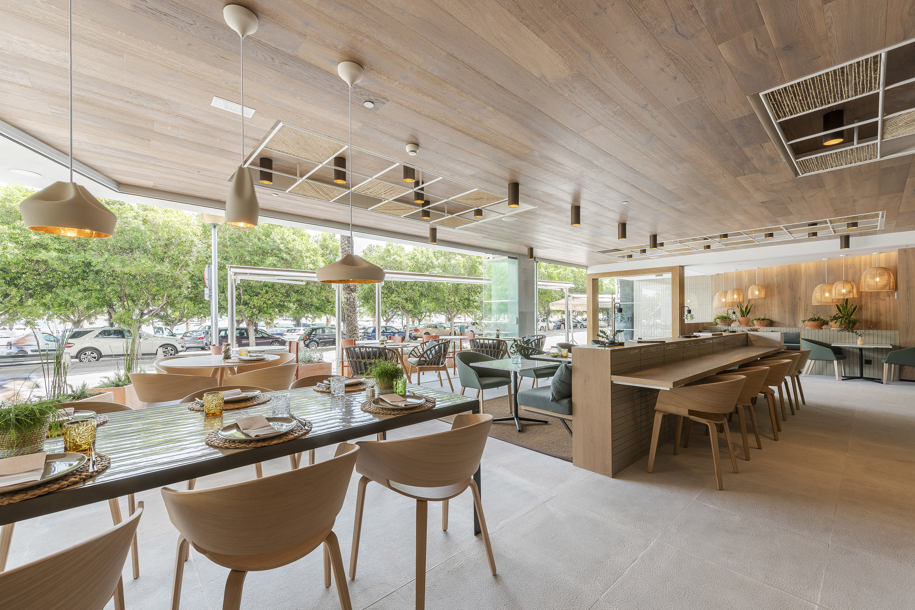 Modern restaurant with wood ceiling, large windows, and diverse seating.