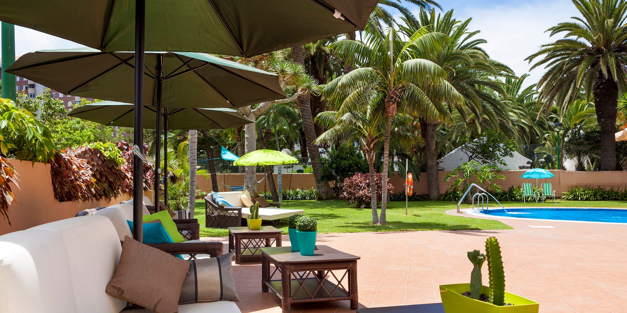a patio with umbrellas and chairs and a pool