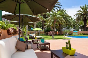 a patio with umbrellas and chairs and a pool