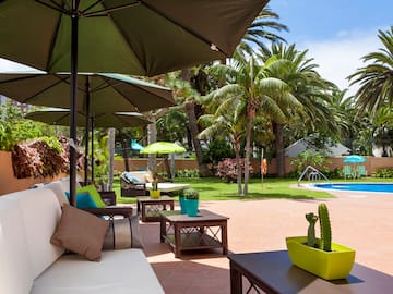 a patio with umbrellas and chairs and a pool