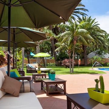 a patio with umbrellas and chairs and a pool