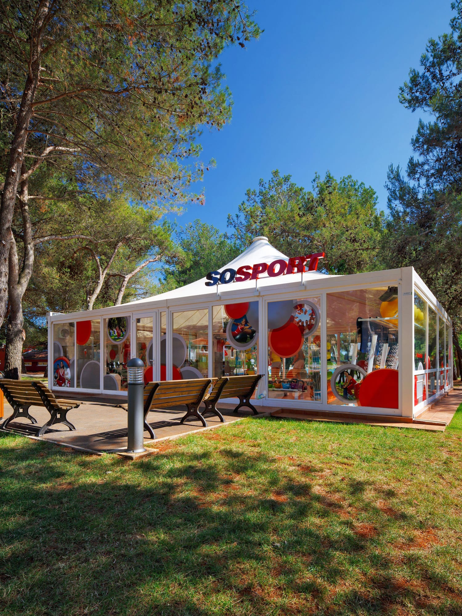 a white tent with red and white balloons in front of trees