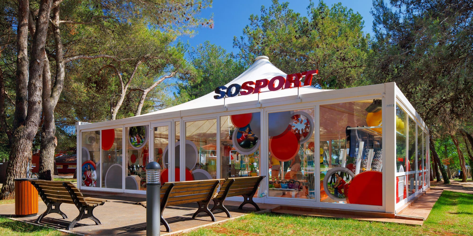 a white tent with red and white balloons in front of trees