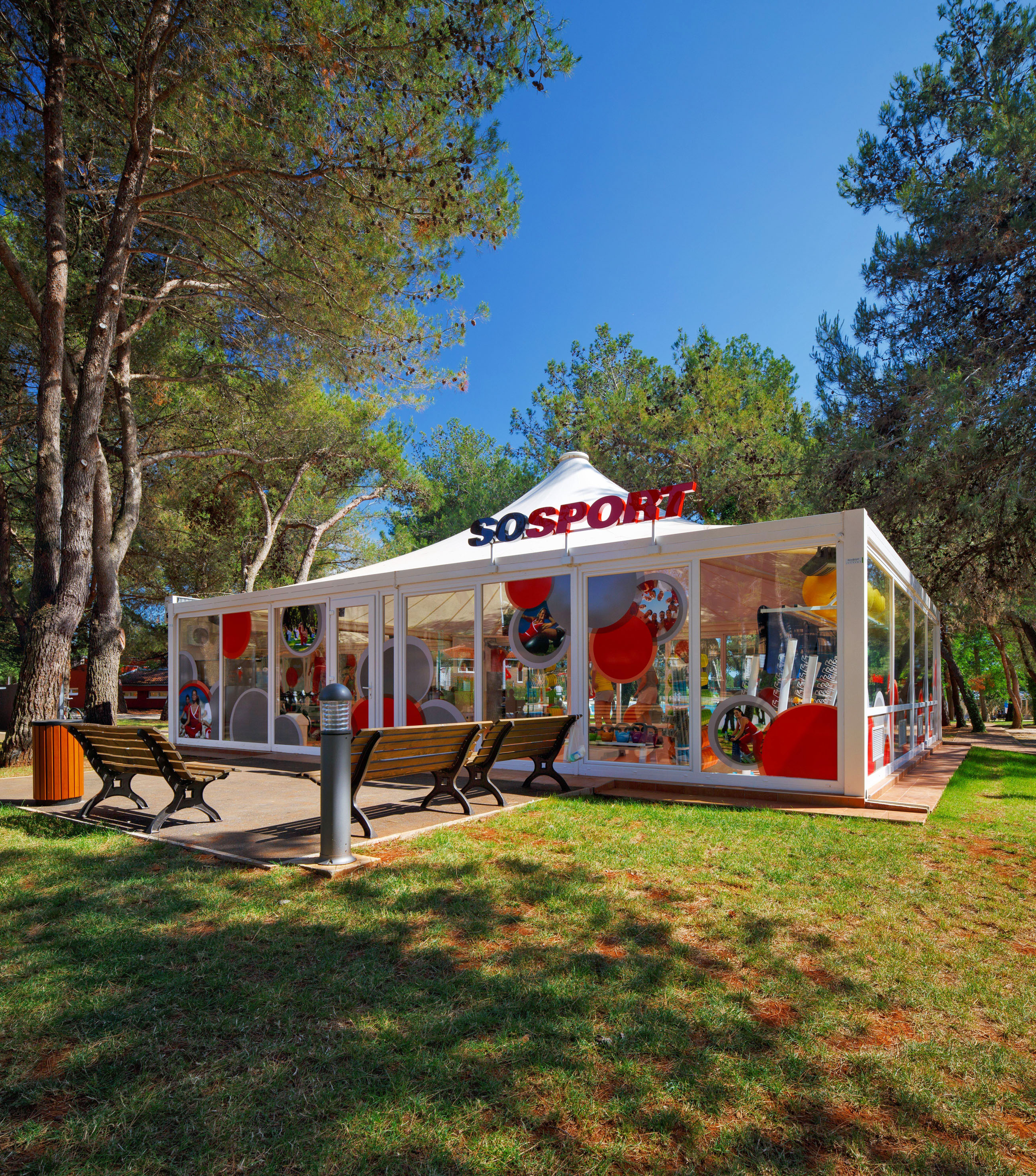 a white tent with red and white balloons in front of trees