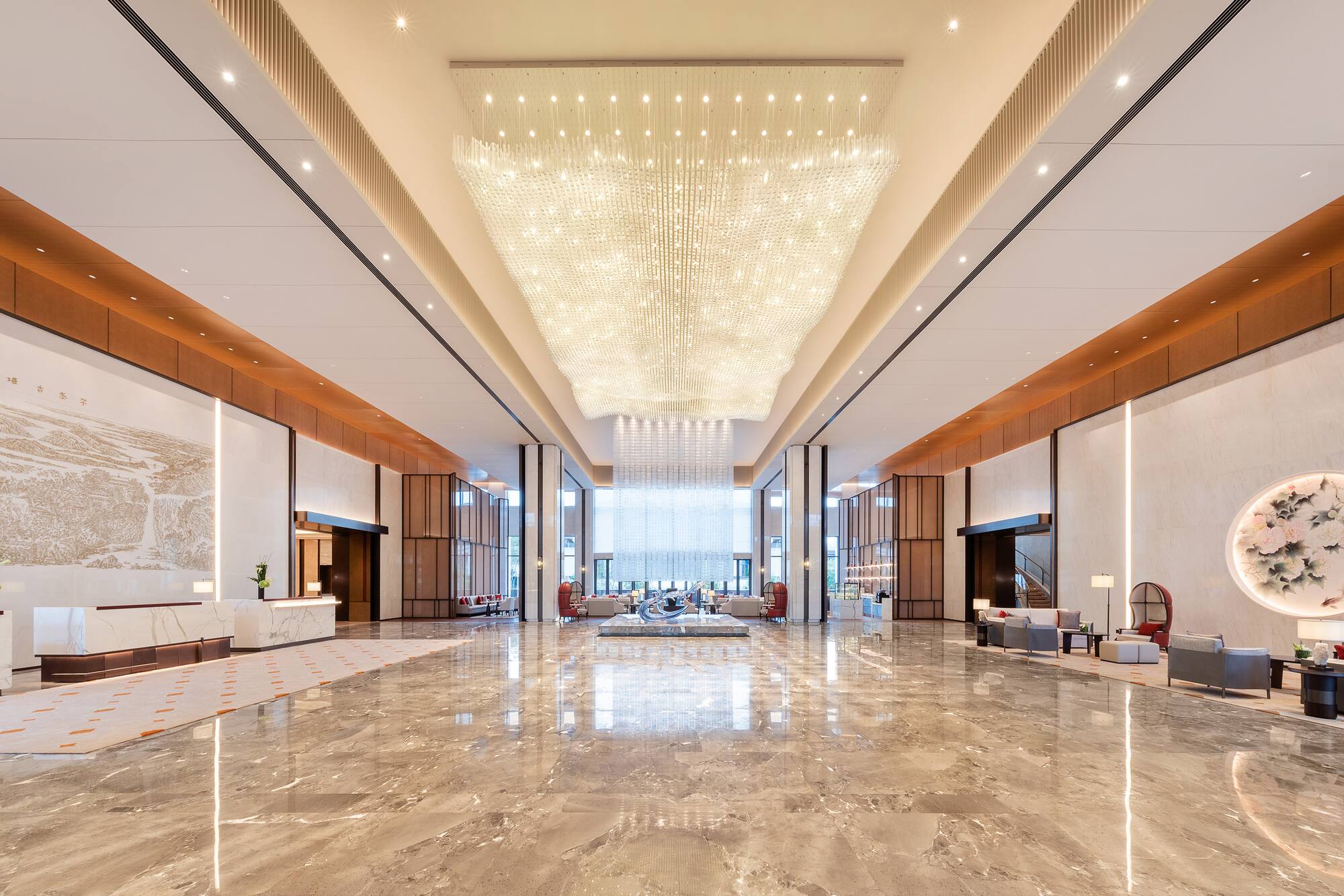 Luxurious hotel reception with grand chandelier, polished marble, modern design.