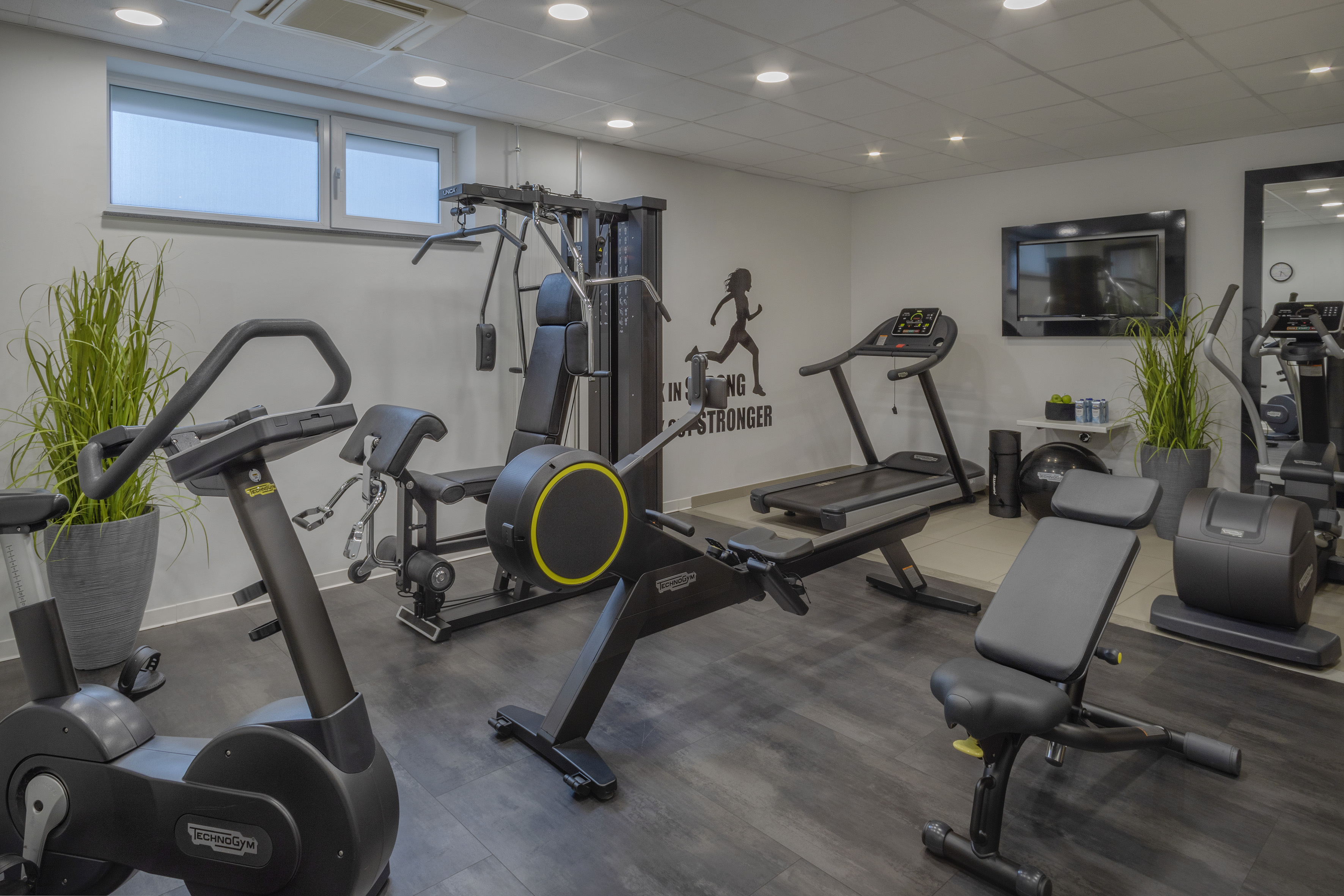 Technogym gym: treadmill, stationary bike, rower, and strength equipment.