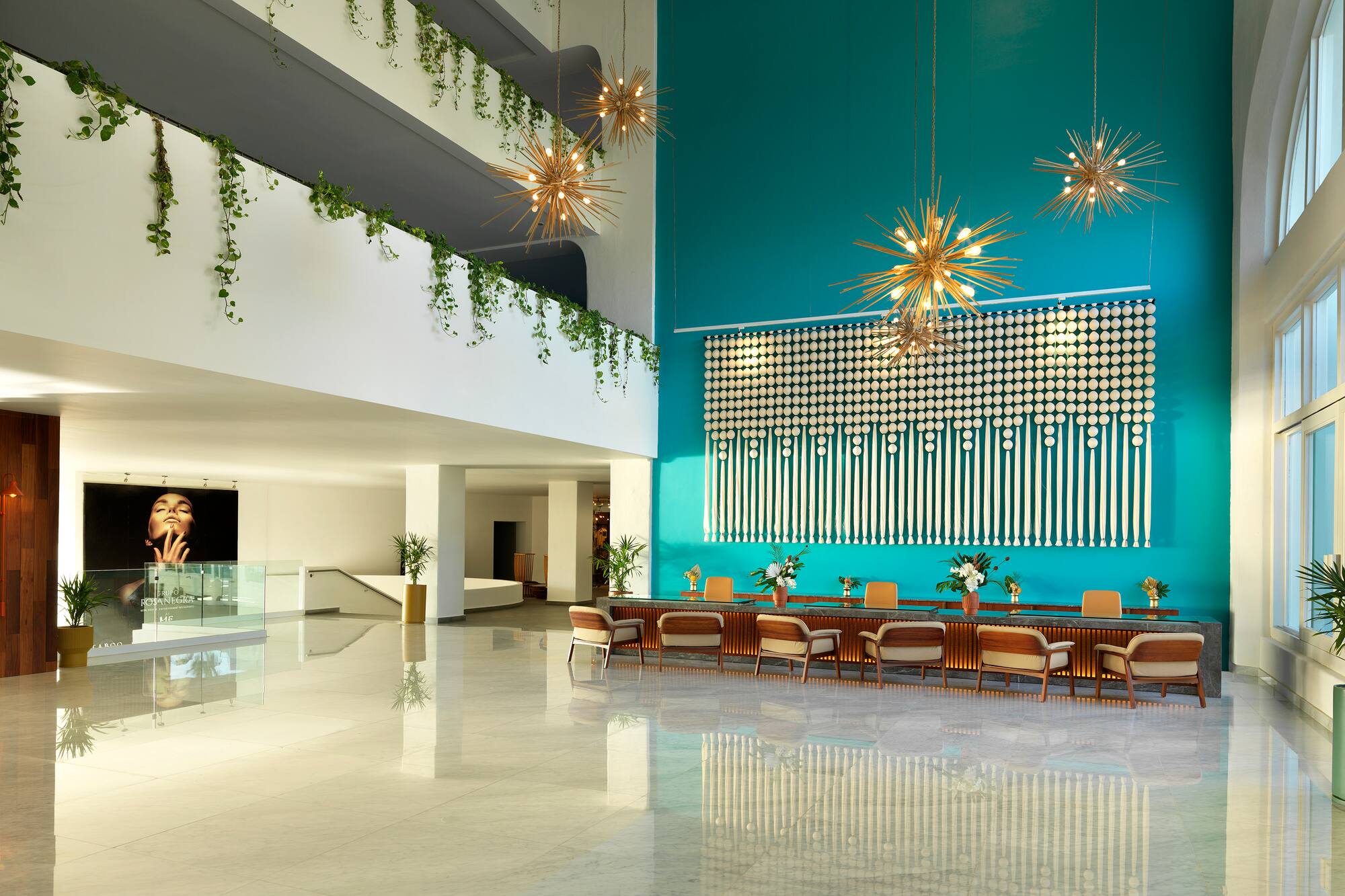 Modern hotel lobby with teal feature wall, sputnik chandeliers, and polished floors.