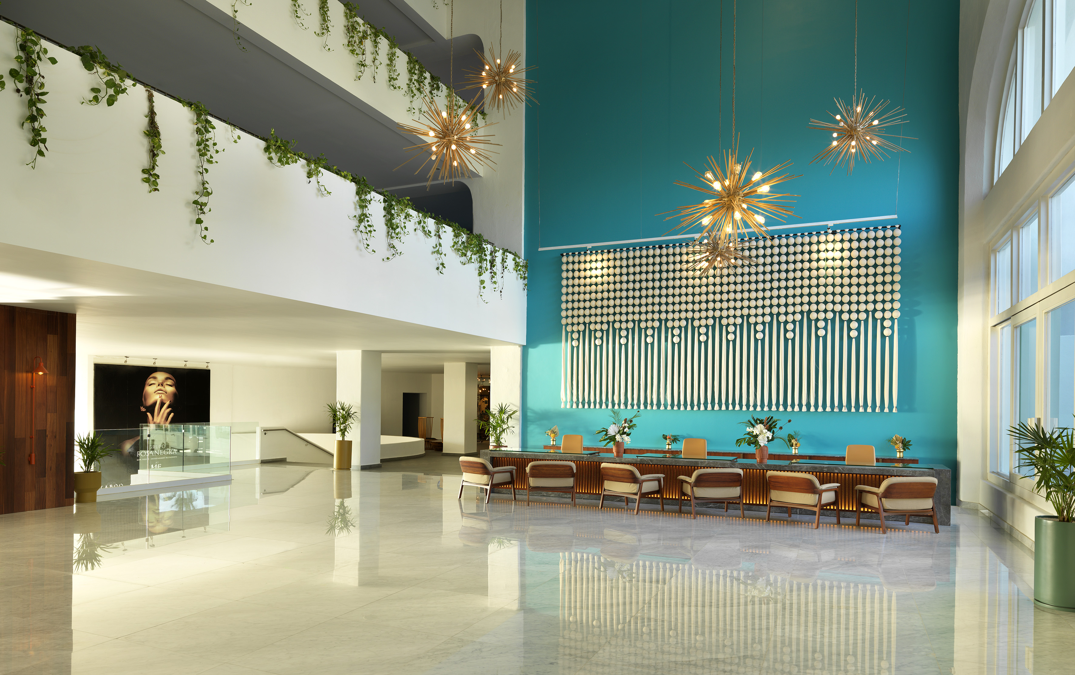 Modern hotel lobby with teal feature wall, sputnik chandeliers, and polished floors.