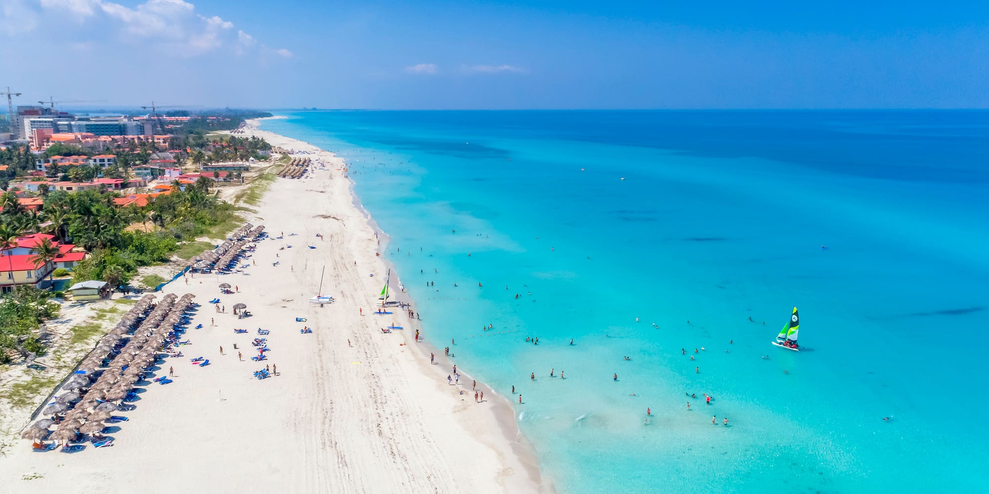 a beach with people and a sailboat