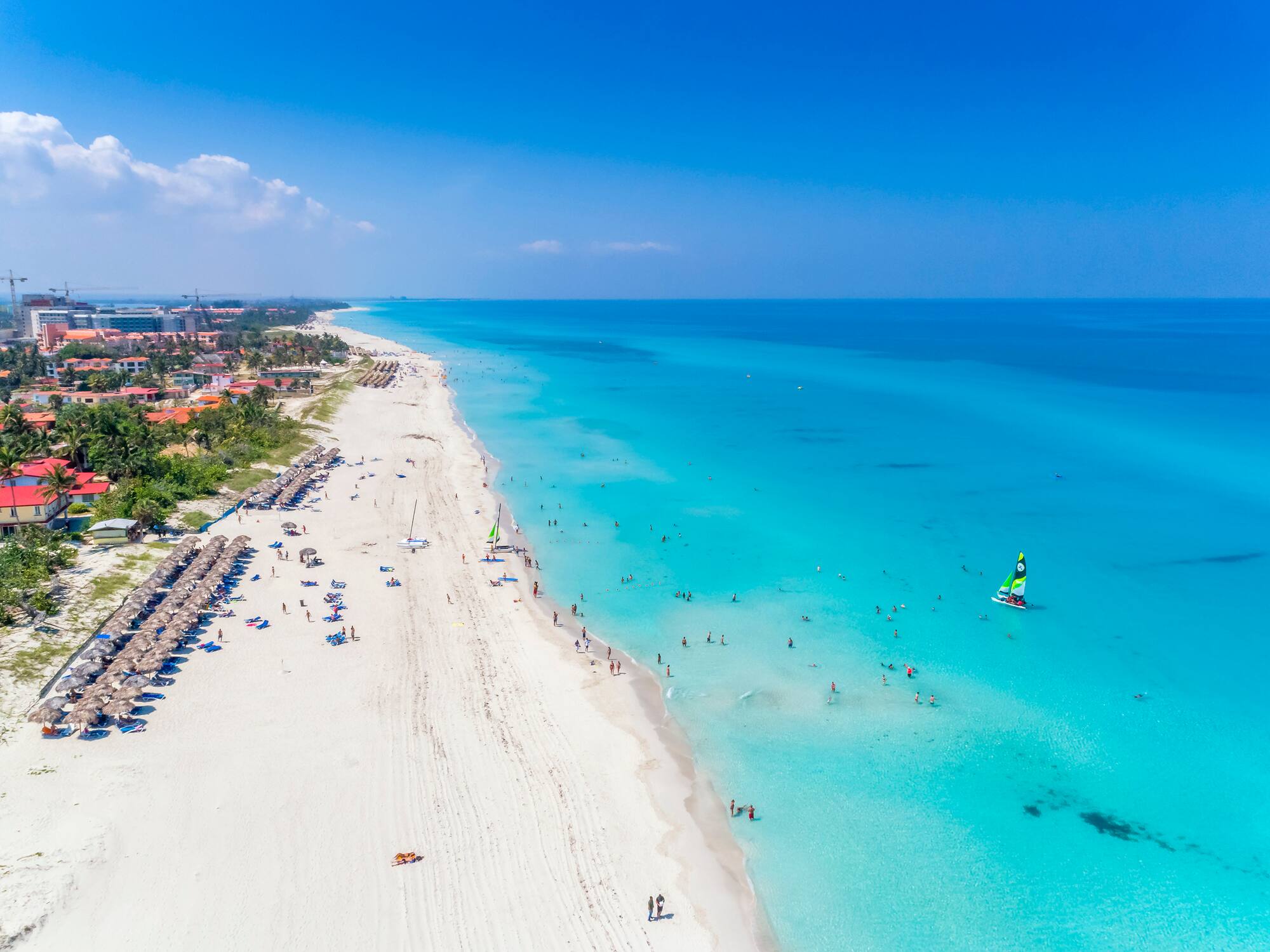 a beach with people and a sailboat
