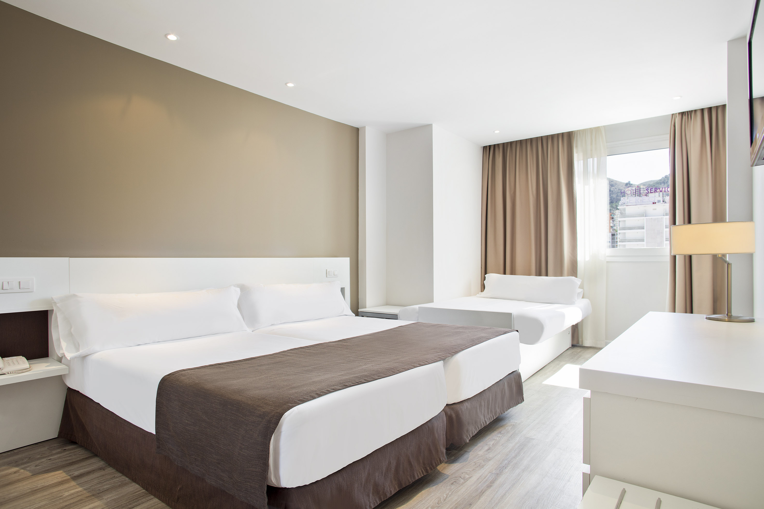 Hotel bedroom with twin beds, white bedding, brown accents, and a daybed.