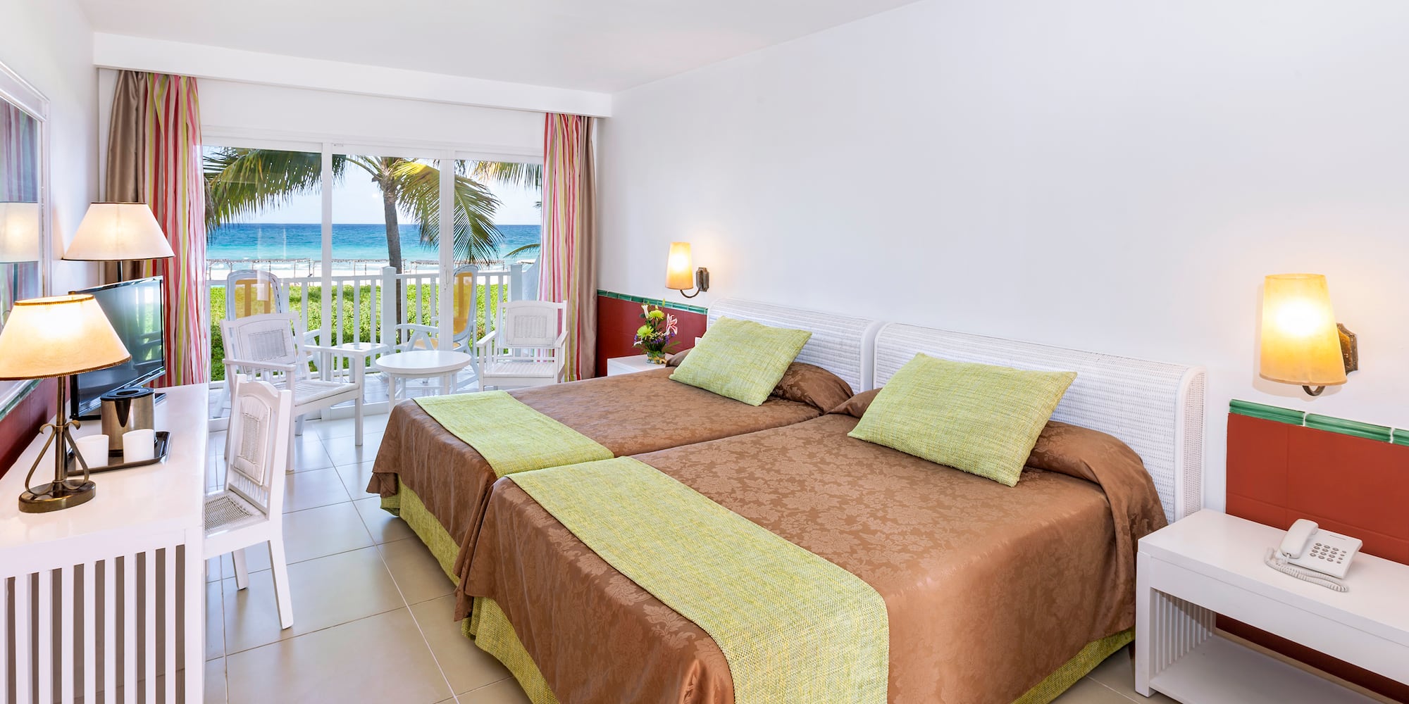 a room with two beds and a balcony overlooking the ocean