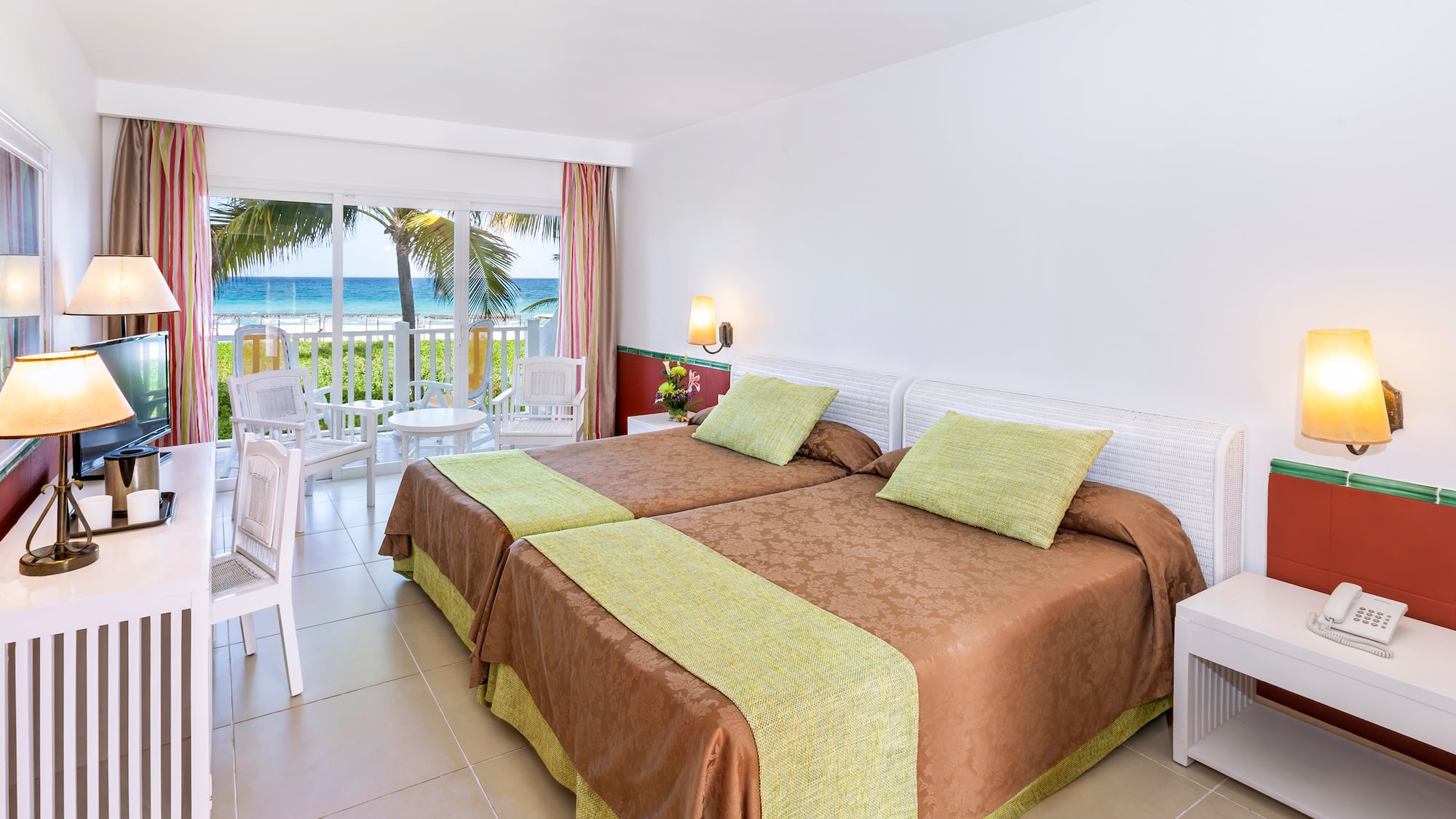 a room with two beds and a balcony overlooking the ocean