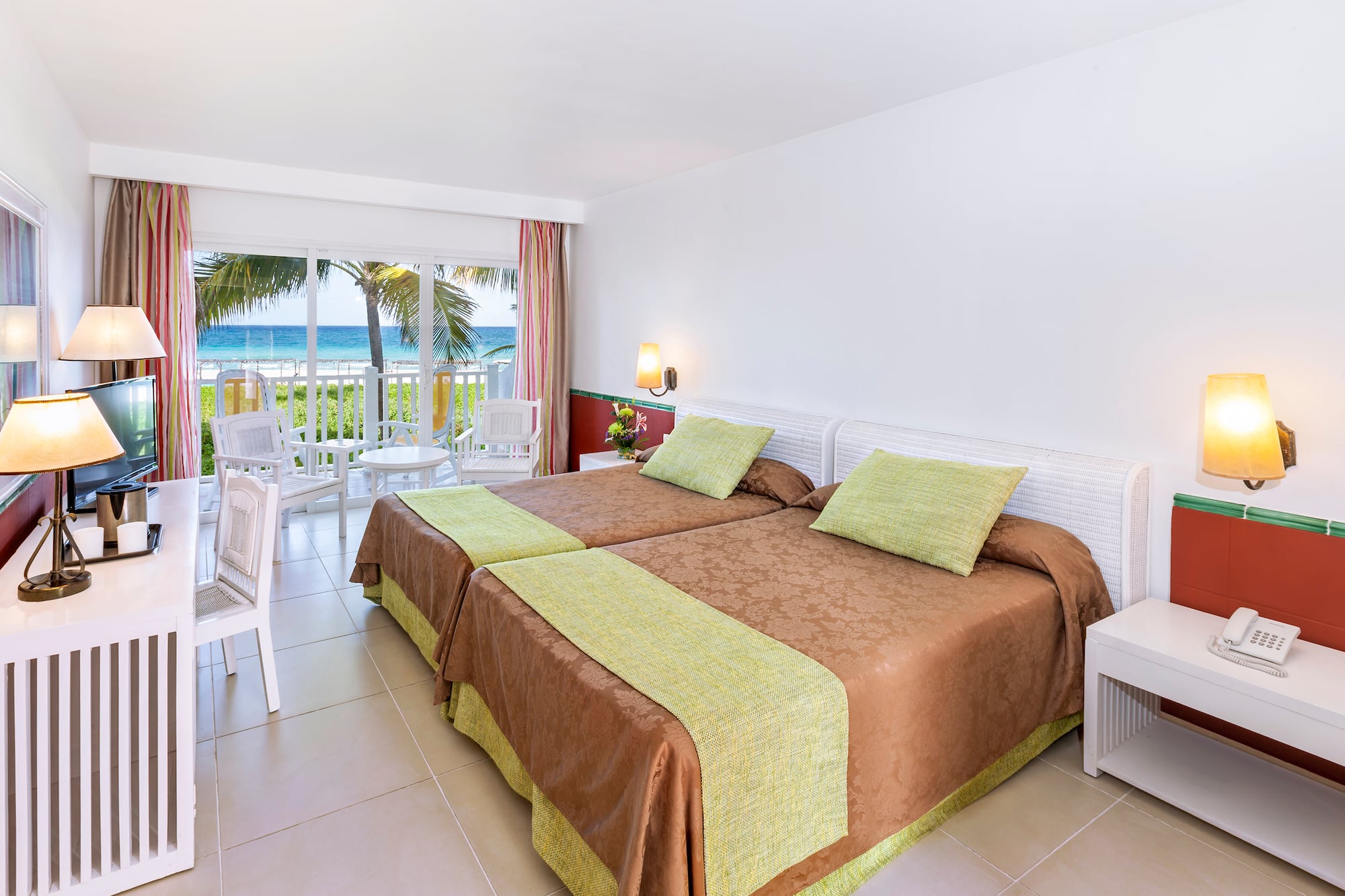 a room with two beds and a balcony overlooking the ocean