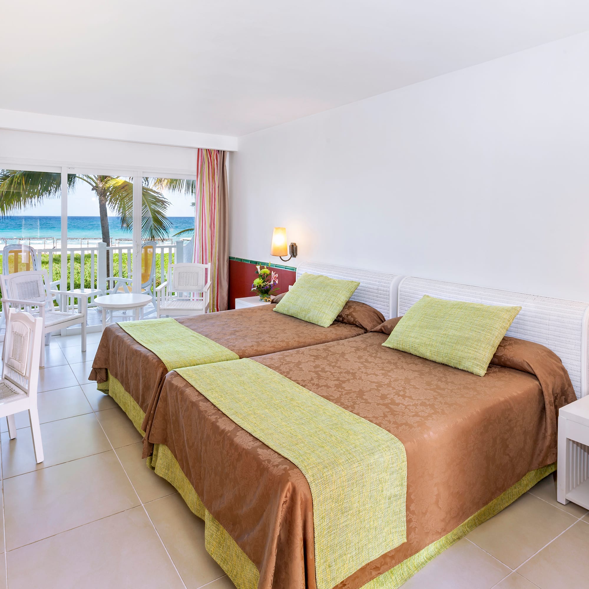 a room with two beds and a balcony overlooking the ocean